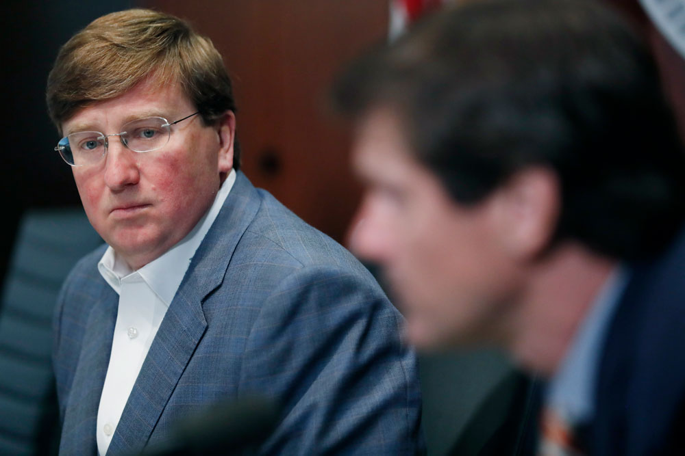 Mississippi Gov. Tate Reeves, left, listens as State Health Officer Dr. Thomas Dobbs speaks about the state's continued efforts in dealing with the coronavirus during his afternoon news conference in Jackson, Mississippi, Tuesday, April 21. 