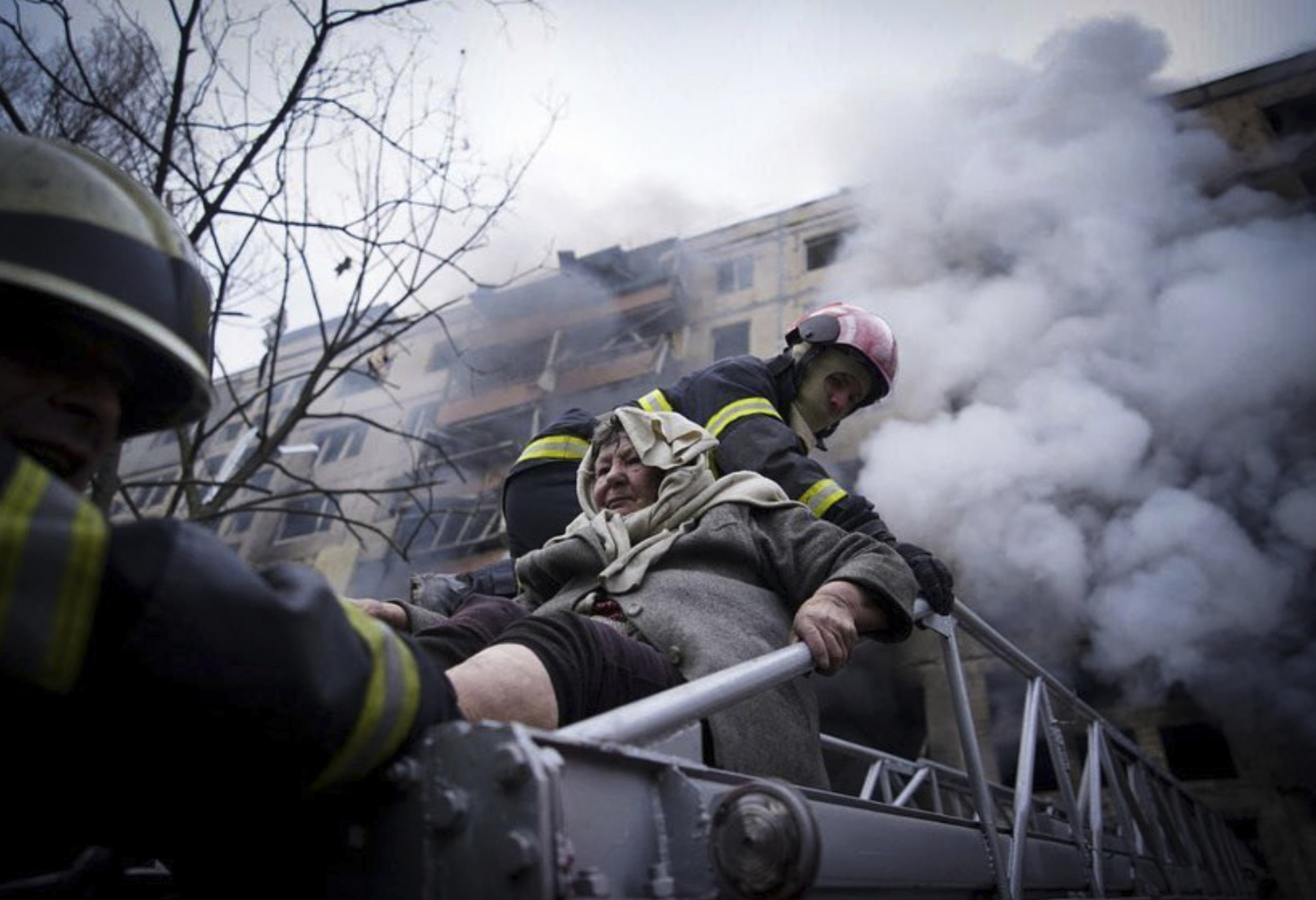 In this photo released by Ukrainian State Emergency Service press service, firefighters evacuate an elderly woman from an apartment building hit by shelling in Kyiv, Ukraine, on March 14.