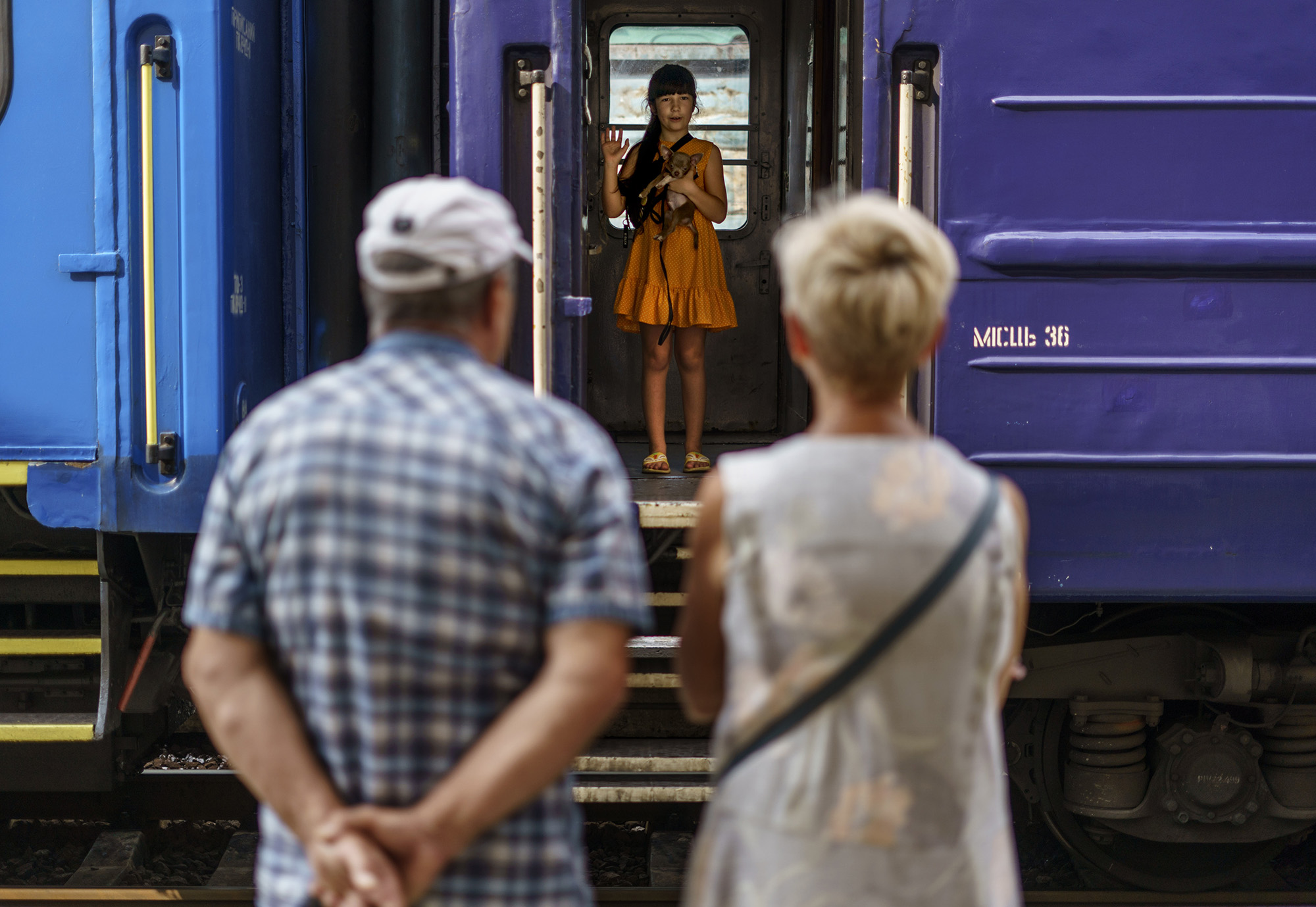 A young girl holds her dog while waving goodbye to her grandparents from an evacuation train departing Pokrovsk, Donetsk region, eastern Ukraine on Tuesday, Aug. 2.