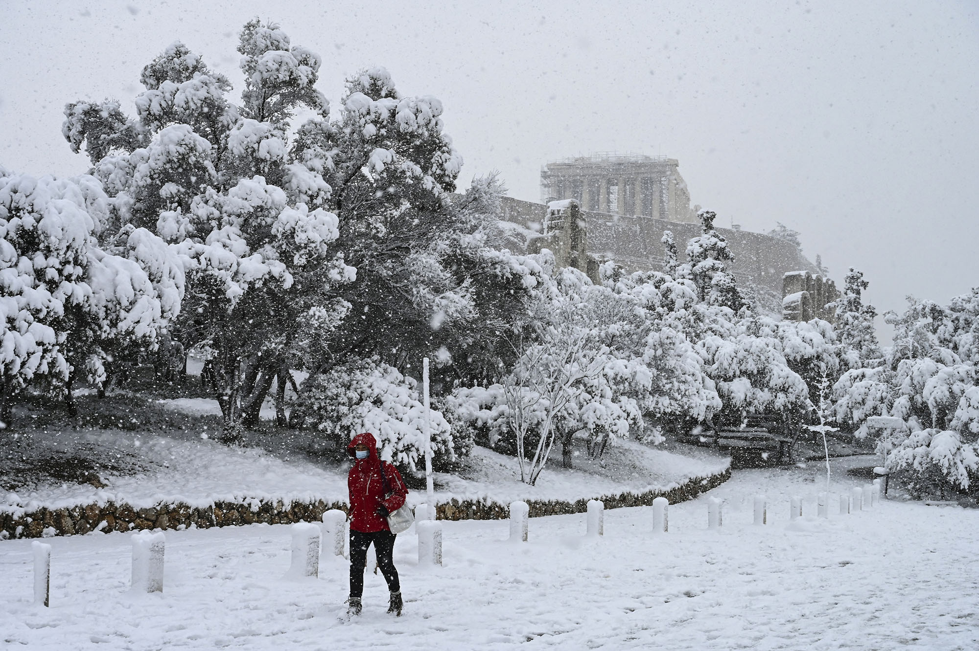 A woman walks past the Parthenon temple during heavy snowfall in Athens, Greece, on February 16, 2021.