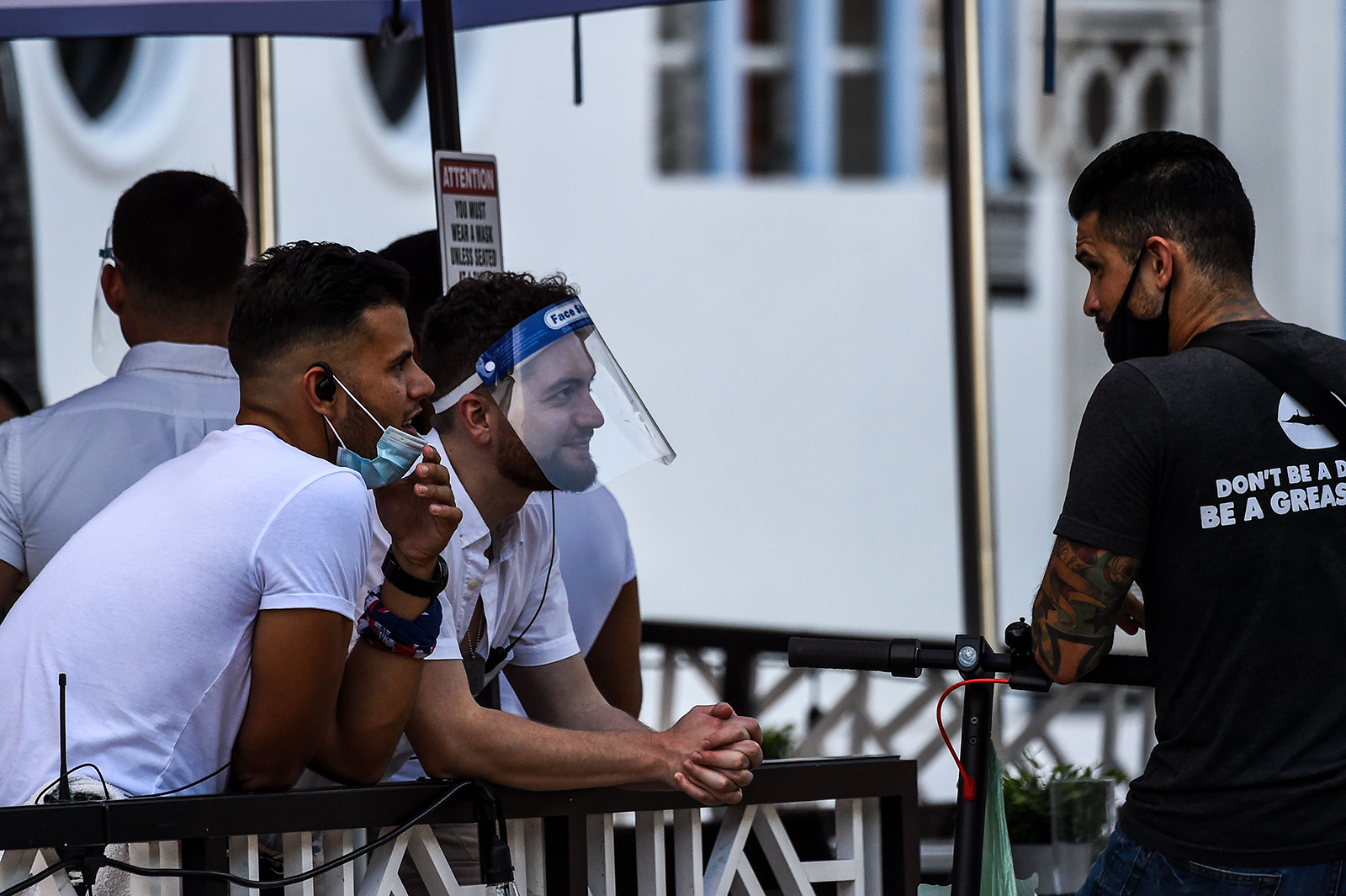 A waiter covers his face with a shield as he chats with another man at a restaurant on Ocean Drive in Miami Beach, Florida on July 14.