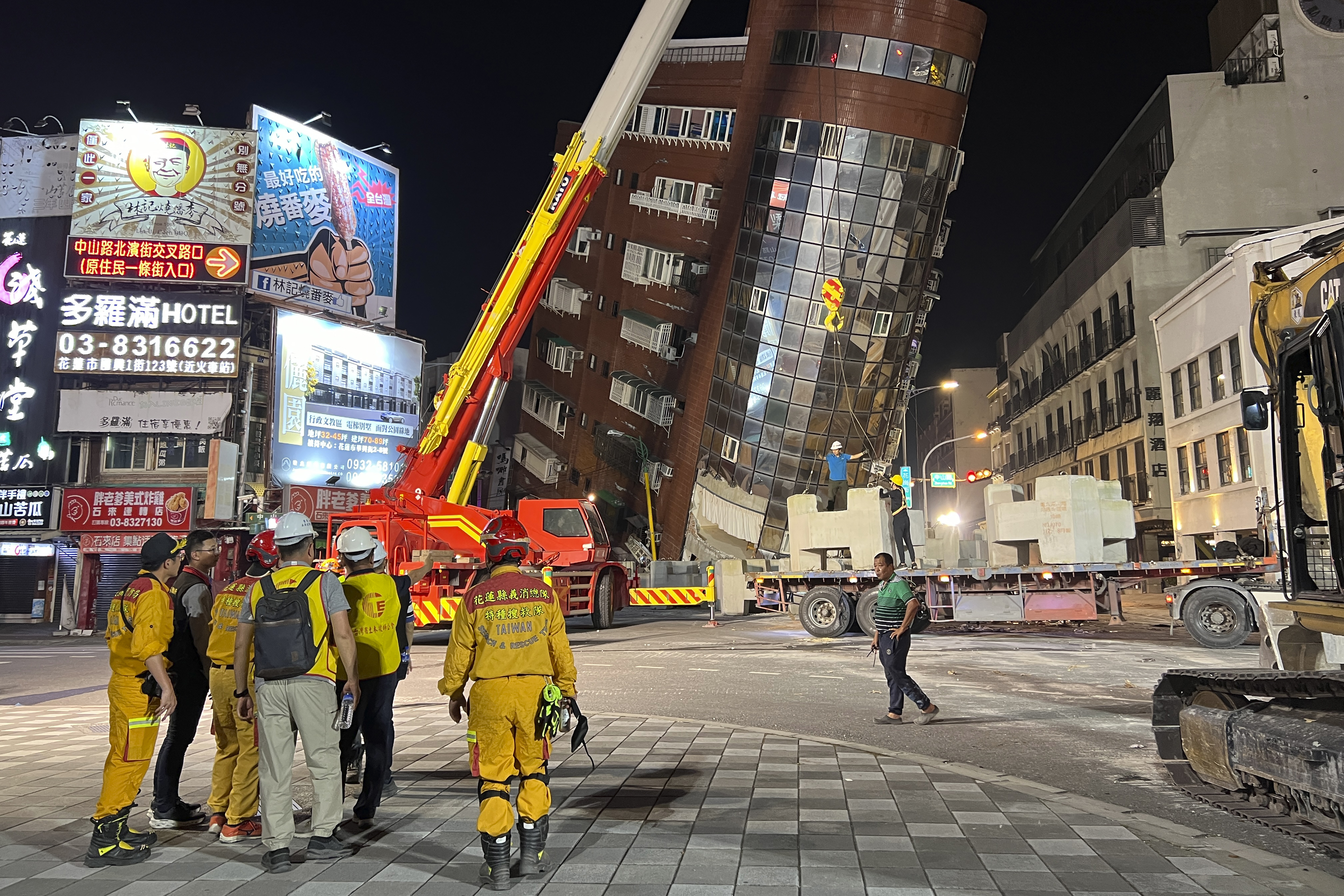 Rescue workers stand near the site of a leaning building in the aftermath of an earthquake in Hualien, Taiwan, on April 3.
