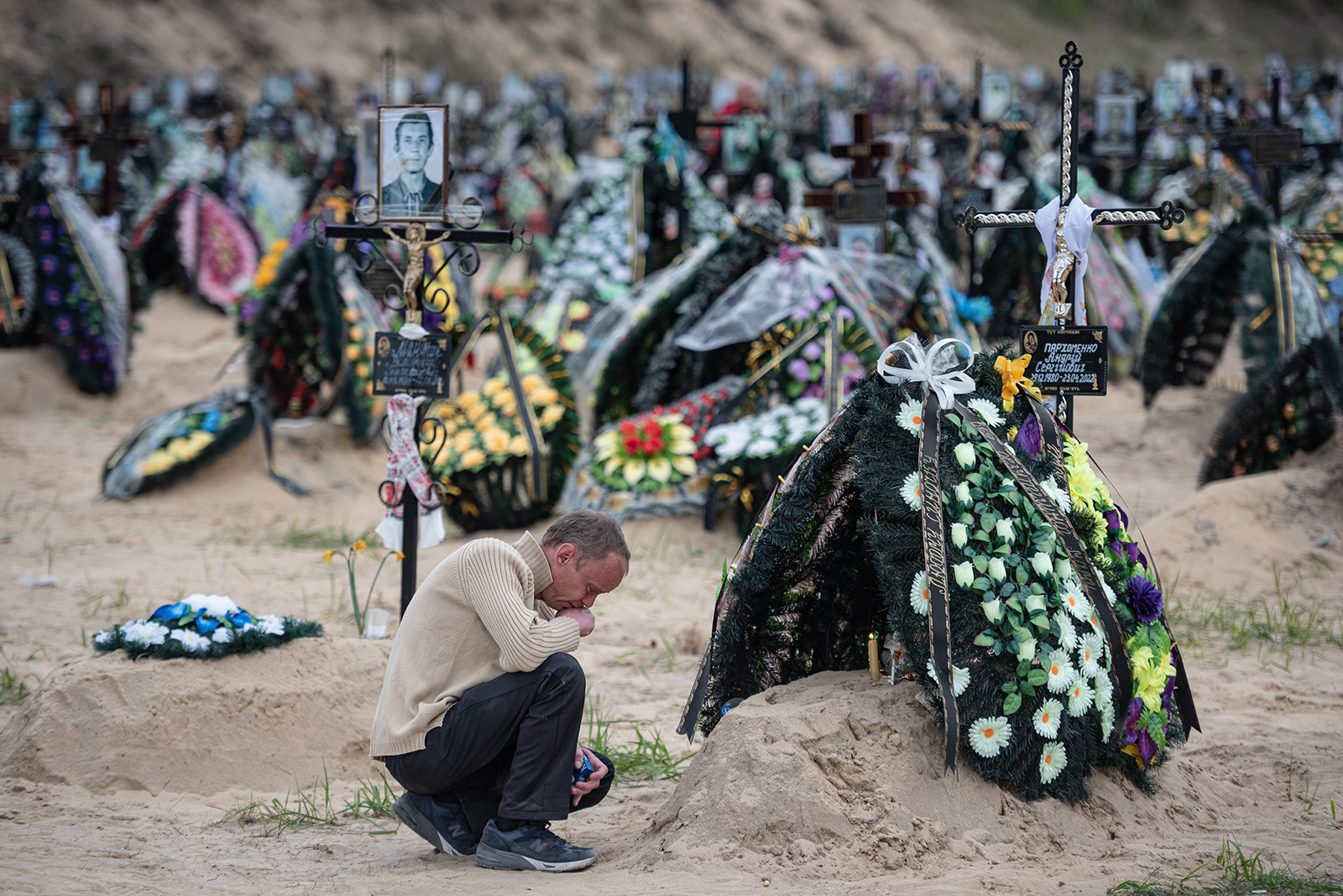 Dmytro, 39, sits by the grave of his childhood friend Andrii Parkhomenko, on May 1, in Irpin, Ukraine. 