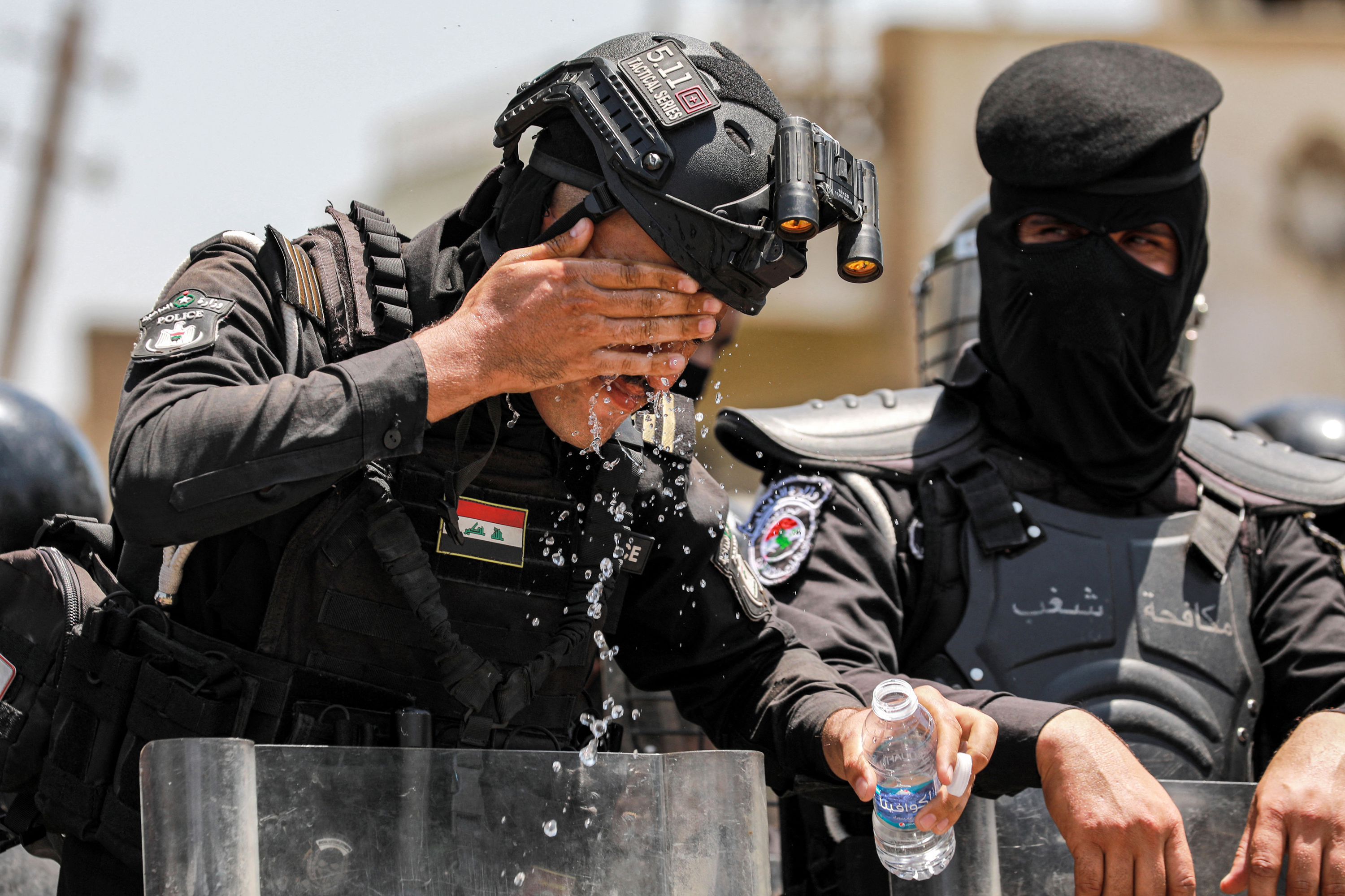 An Iraqi security forces member rinses his face with water from a bottle to cool off during a demonstration against water scarcity and power outages in Baghdad, on Tuesday.