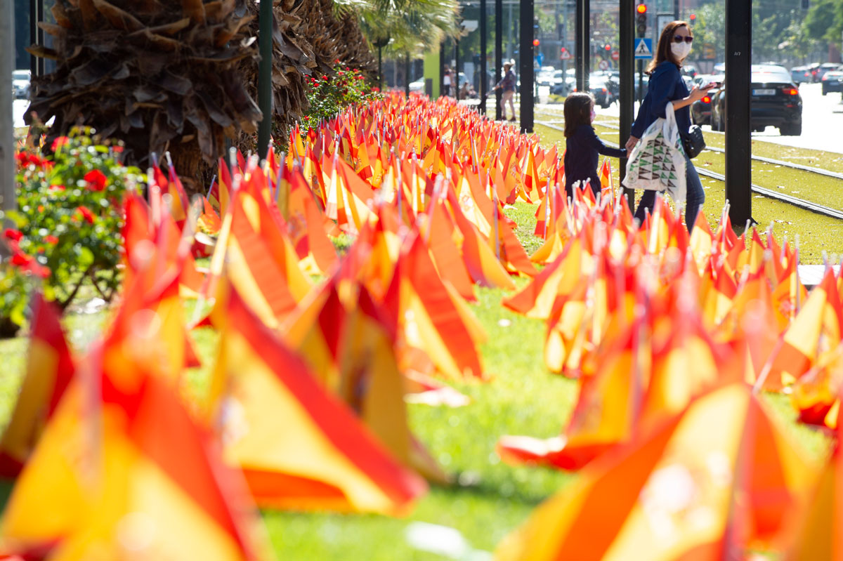 A woman walks with her daughter next to an installation at Isidoro Medina Park by the National Association of Victims and People Affected by Coronavirus (ANVAC) on October 18, in Murcia, Spain. The Spanish flags are a tribute to COVID-19 deaths in the country.