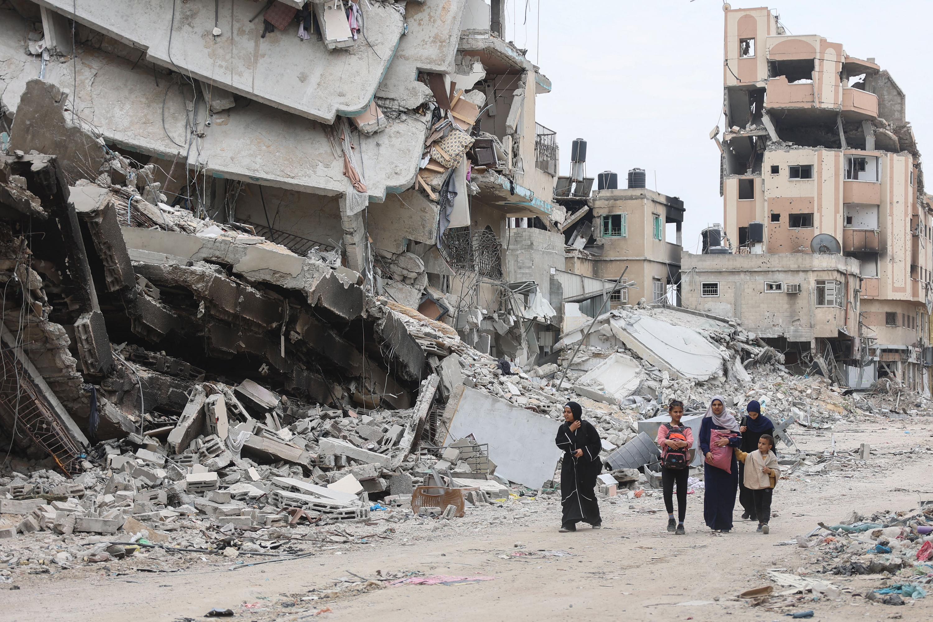 Palestinian women and children walk past the ruins of buildings destroyed by earlier Israeli bombardment in Gaza City on April 8.