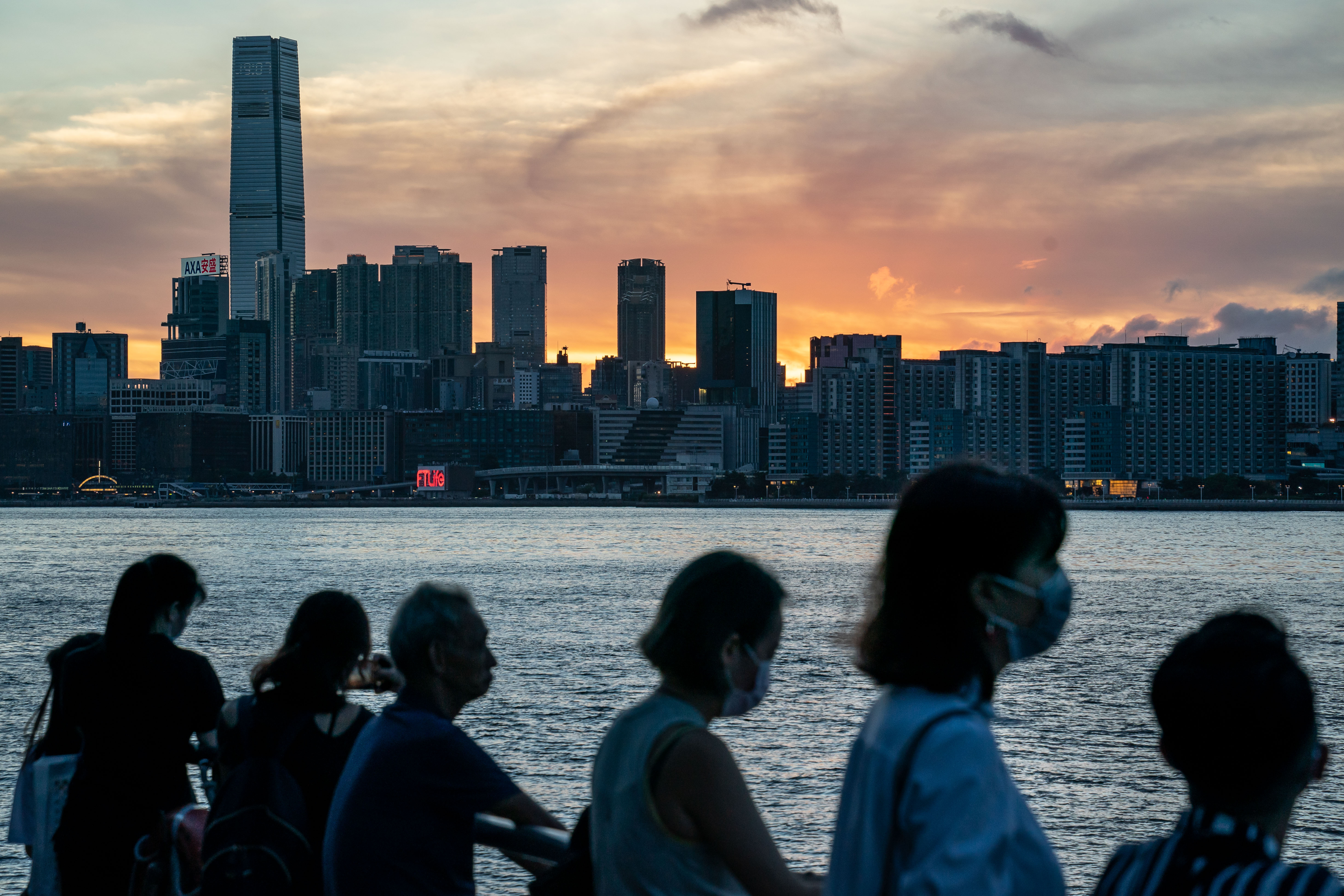 People stand by a harbour in Hong Kong during sunset on July 16.