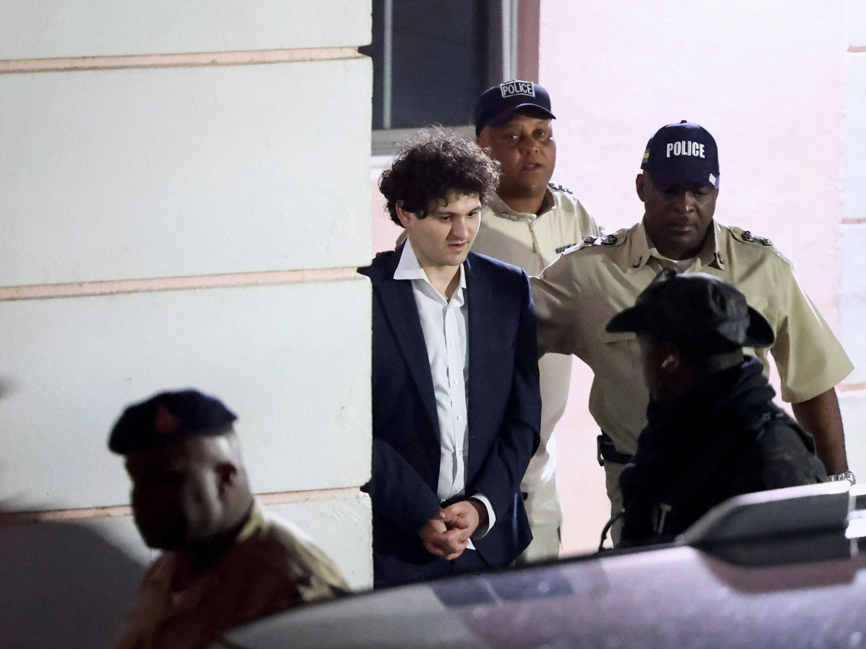 Sam Bankman-Fried is escorted out of the Magistrate Court building after his arrest, in Nassau, Bahamas, on December 13, 2022.