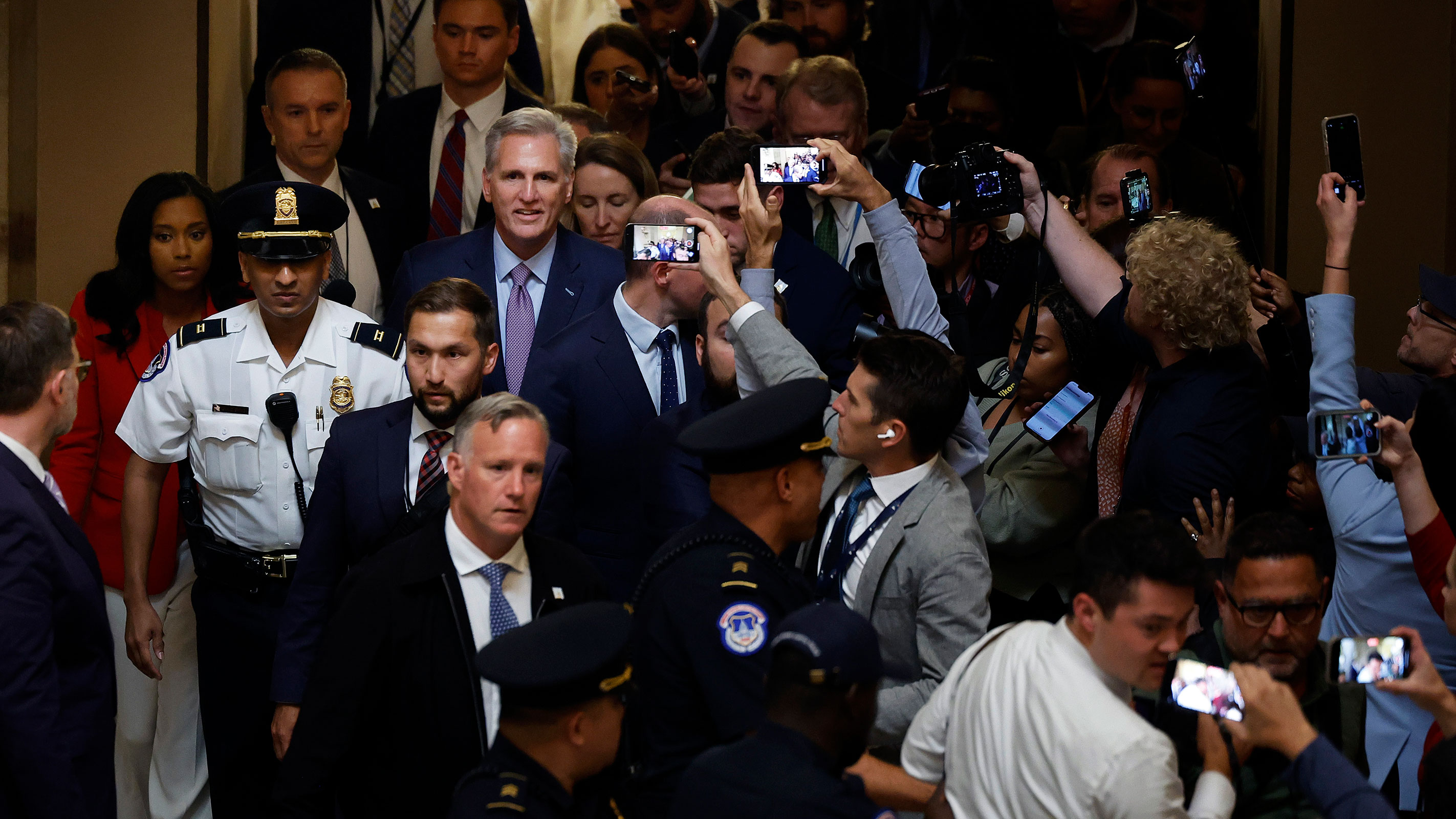 Former Speaker of the House Kevin McCarthy is surrounded by staff, security and journalists as he walks through Statuary Hall after he was ousted at the Capitol on October 3, in Washington, DC.