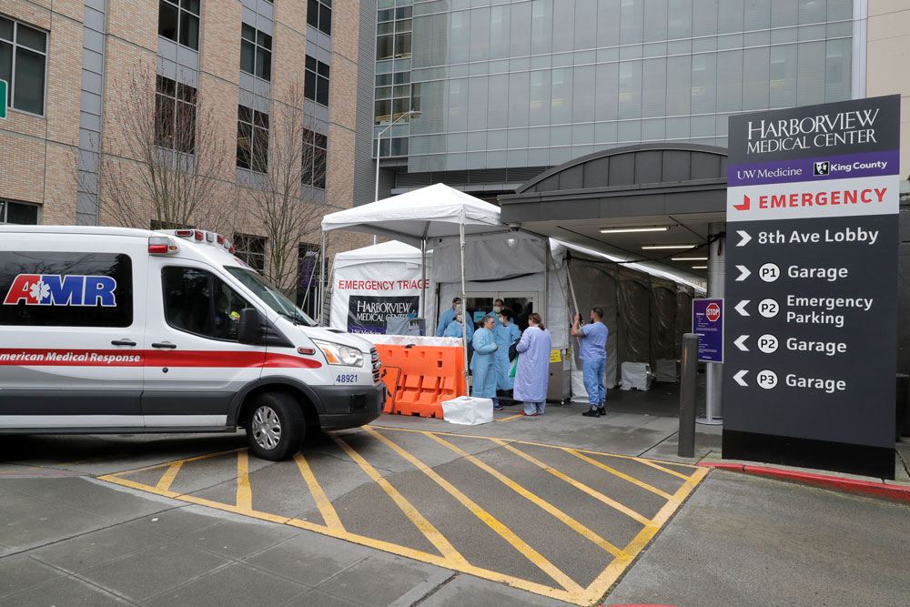 An ambulance pulls up as nurses outside a triage tent for the Emergency Department at the Harborview Medical Center hospital put on gowns and other protective gear at the start of their shift on Thursday, April 2, in Seattle. 