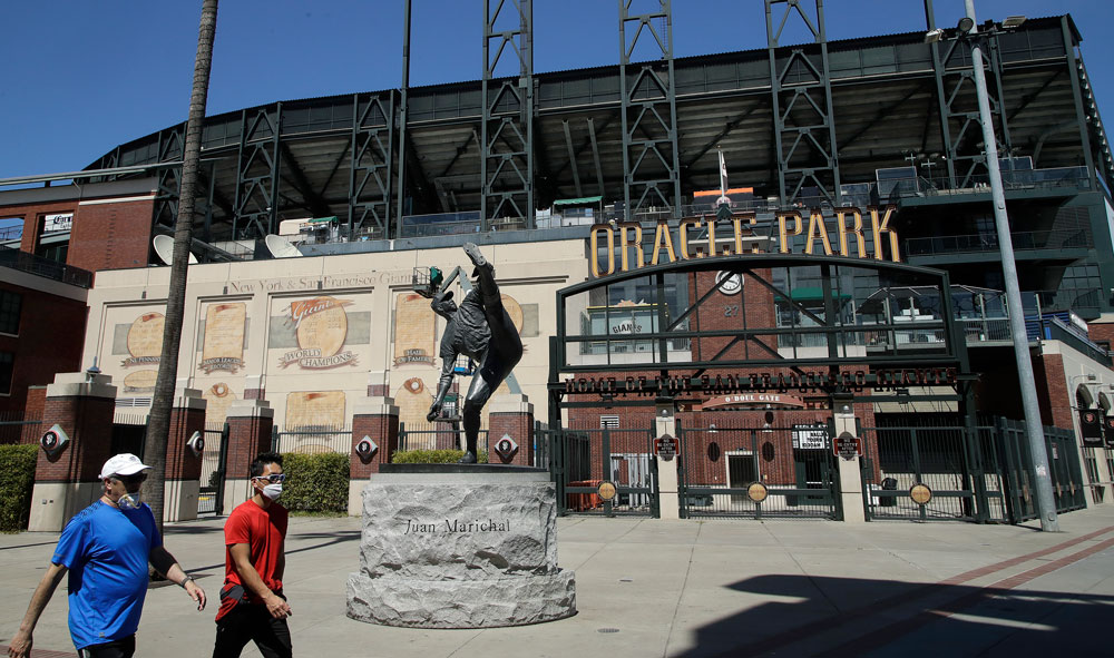 Masked men walk past a closed Oracle Park, home to the San Francisco Giants, on Wednesday, April 15, in California.