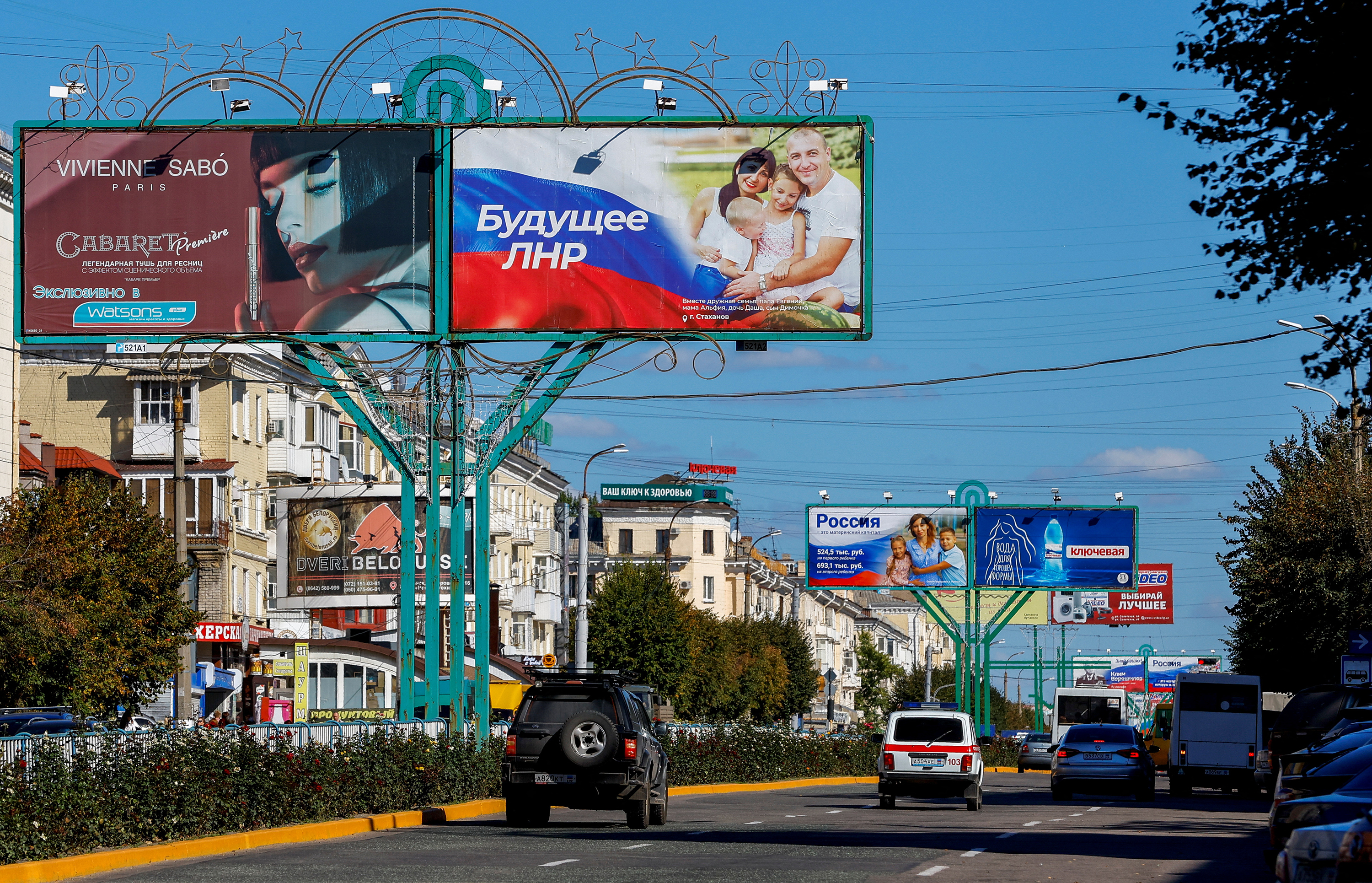 Veículos passam por placas de publicidade, incluindo painéis exibindo slogans pró-Rússia, em uma rua durante o conflito Rússia-Ucrânia em Luhansk, Ucrânia, em 20 de setembro.