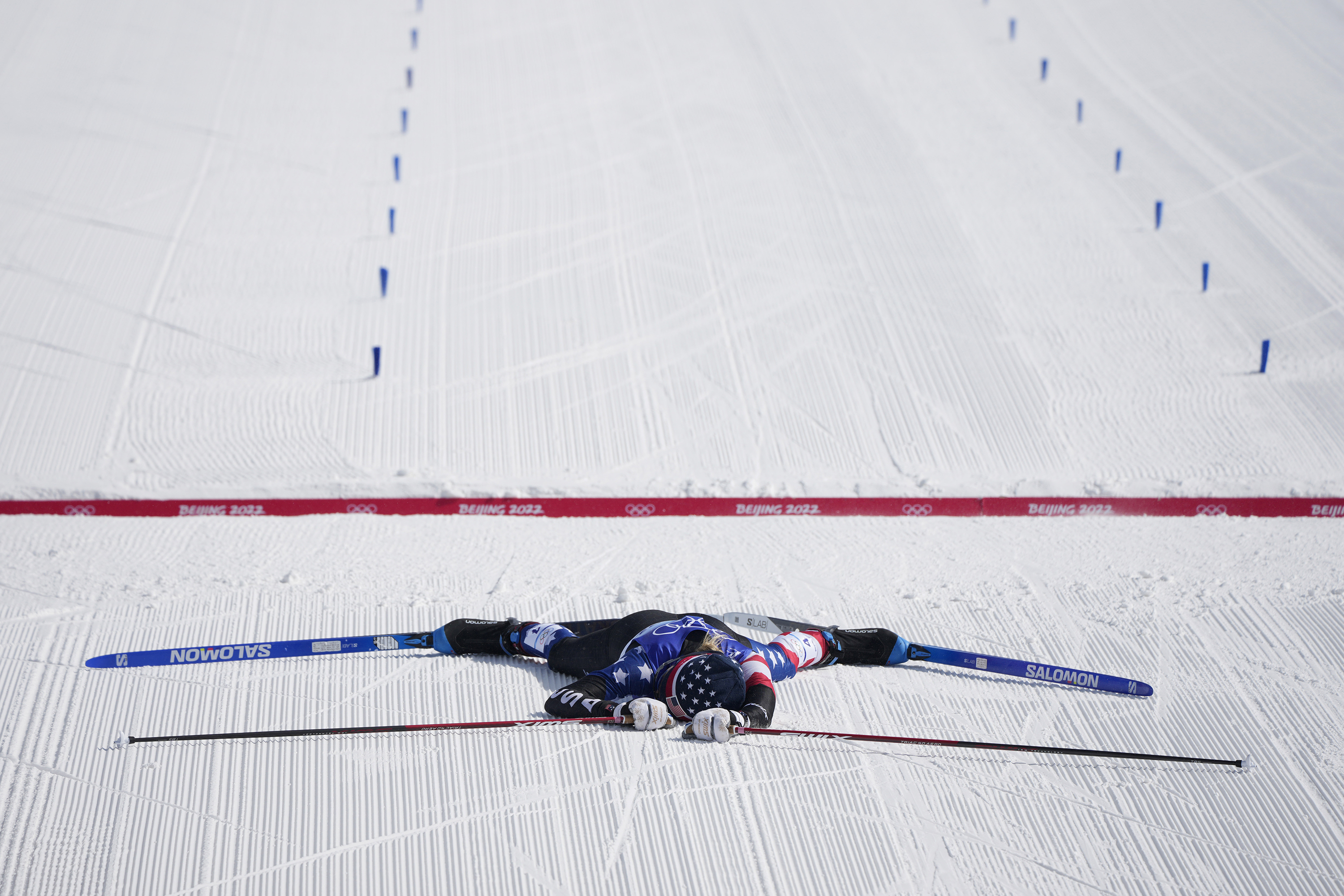 American cross-country skier Jessie Diggins lies on the snow after crossing the finish line of the 30-kilometer mass start event on Sunday. She won the silver, finishing behind Norway's Therese Johaug.