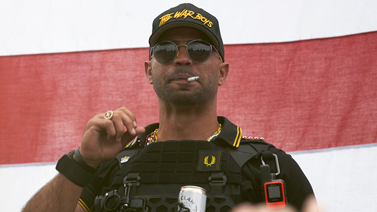 Proud Boys leader Enrique Tarrio wears a hat that says The War Boys and smokes a cigarette at a rally in Delta Park on Saturday, September 26, in Portland, Oregon.