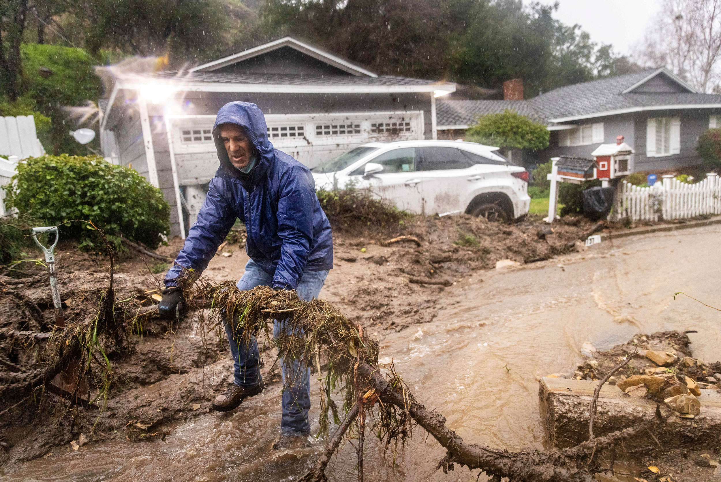 Jeffrey Raines clears debris from a mudslide at his parent's home in Los Angeles on Monday. 