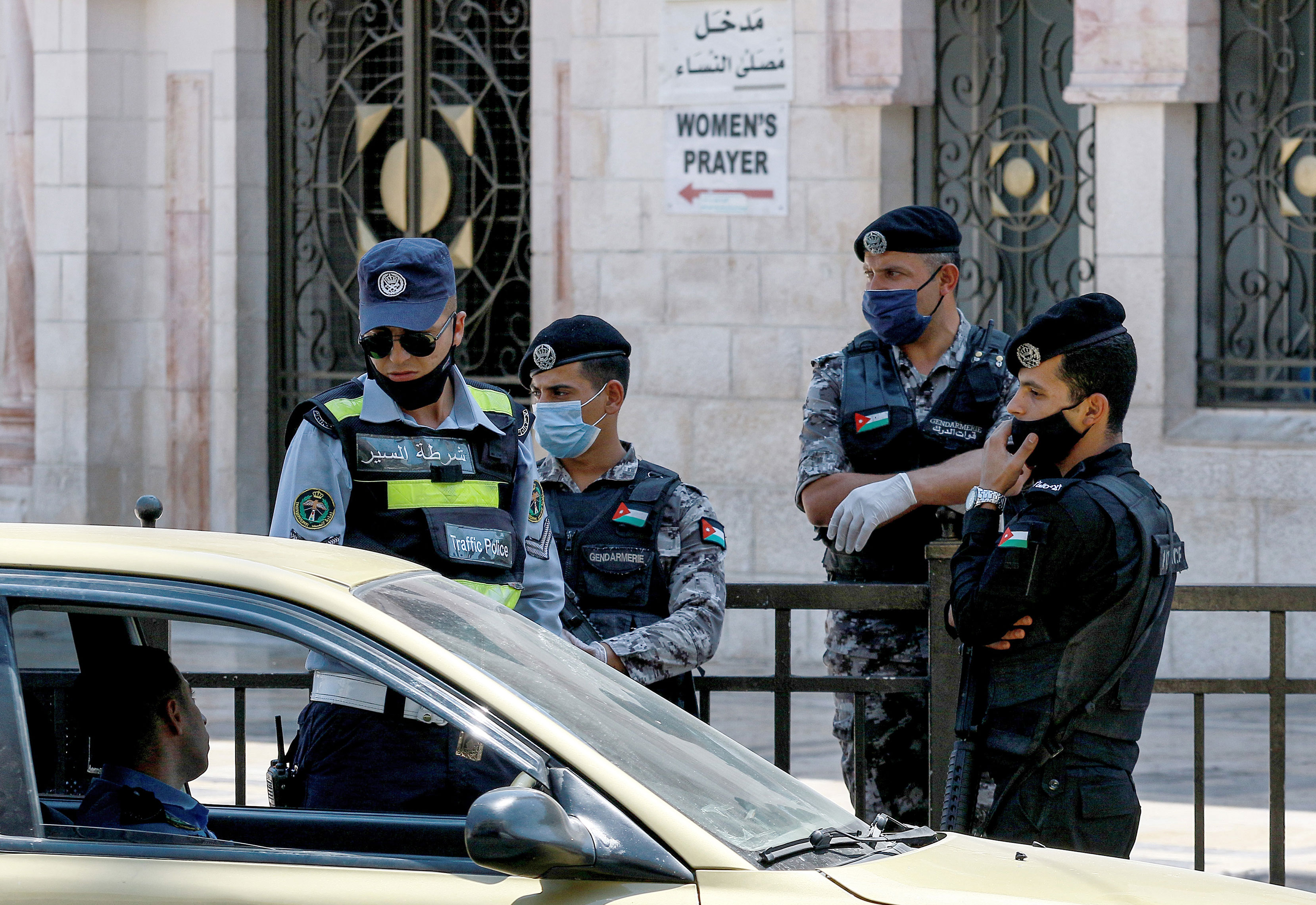 Police officers stop a vehicle outside the Grand Husseini Mosque in Amman, Jordan, while enforcing a curfew on August 28.