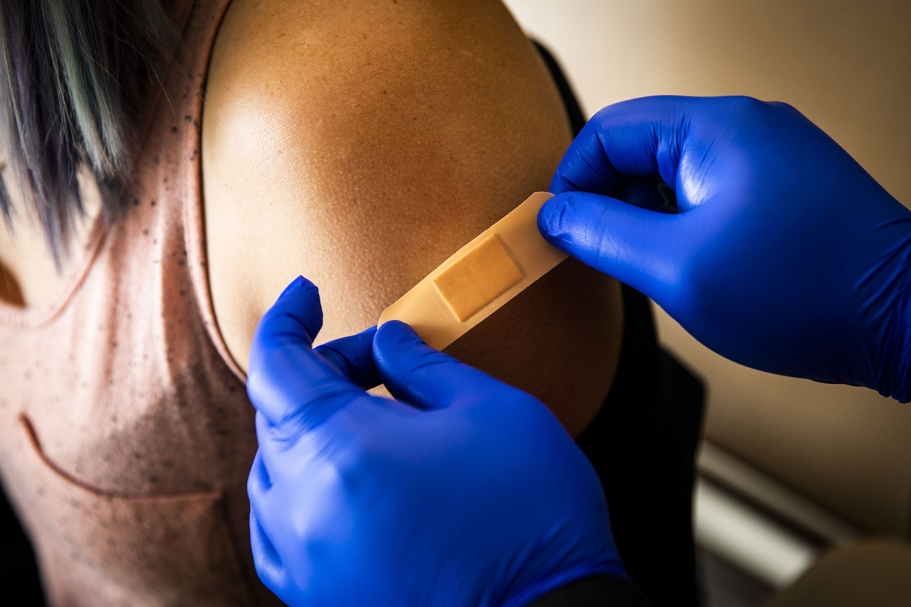 A healthcare worker places a band-aid on a patient after administering a dose of the Pfizer Covid-19 vaccine in Boston on June 17.