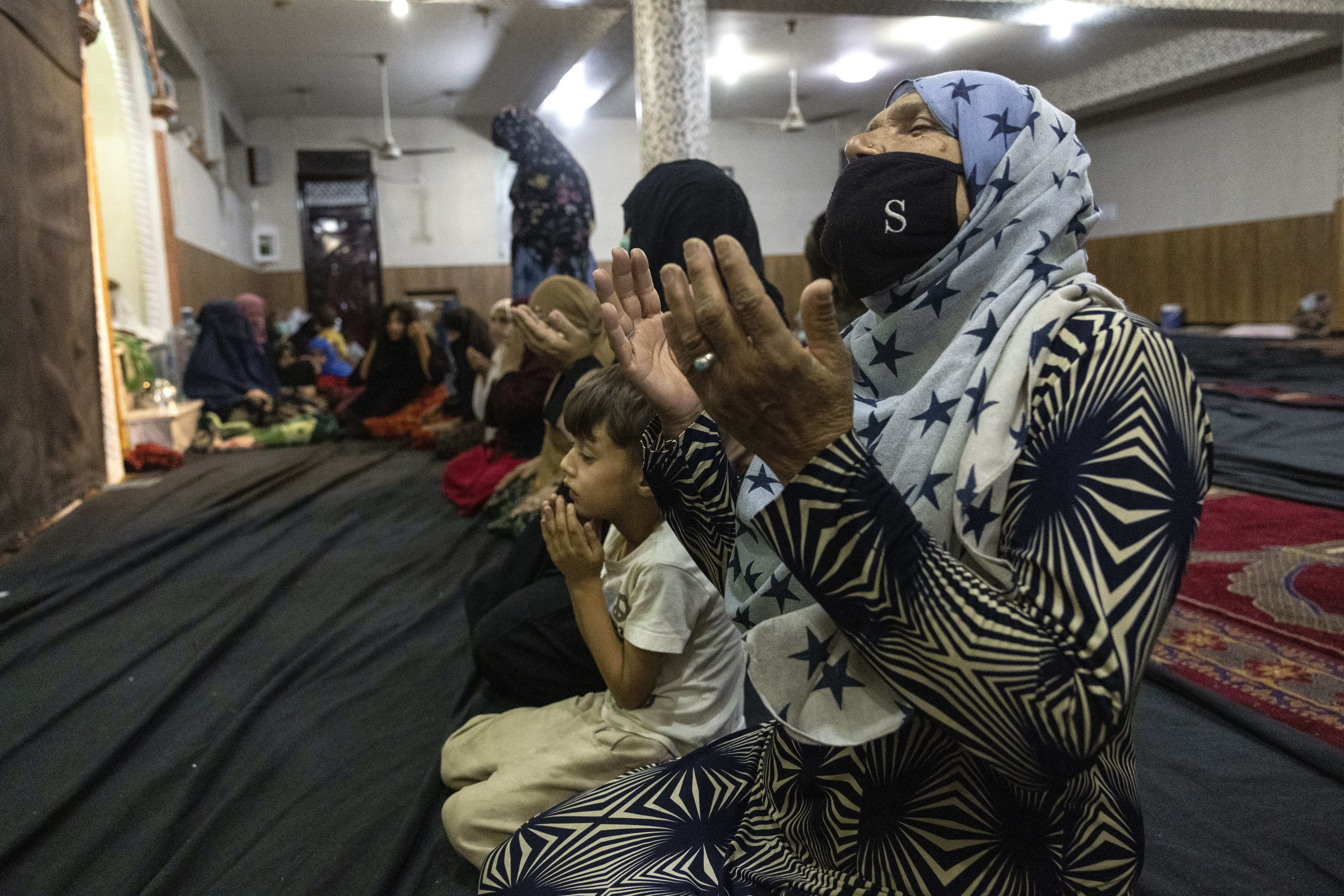 Women and children from Kunduz pray at a mosque in Kabul where they are seeking shelter on August 13, 2021.
