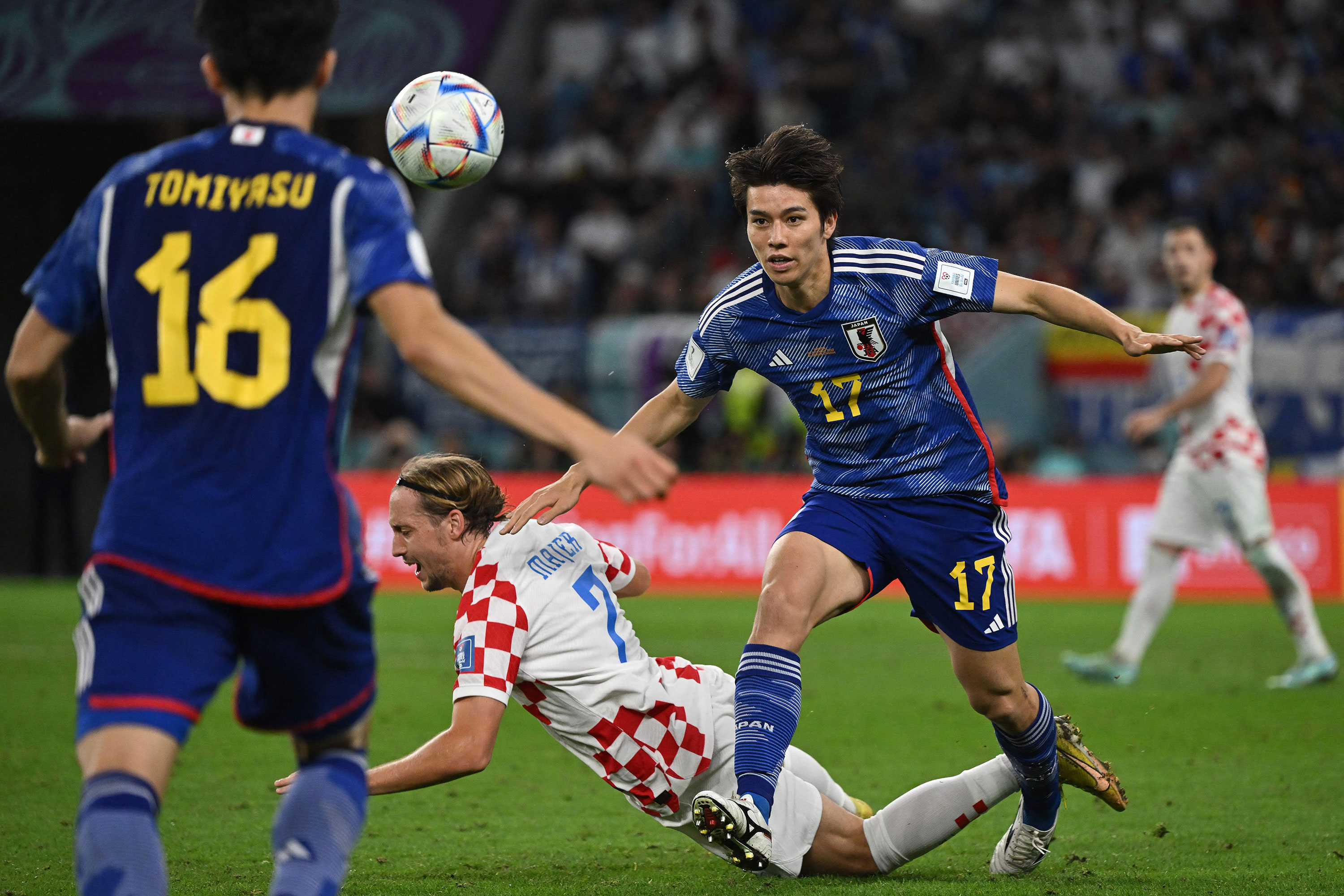Croatia's Lovro Majer, center, falls on the pitch past Japan's Ao Tanaka, right.
