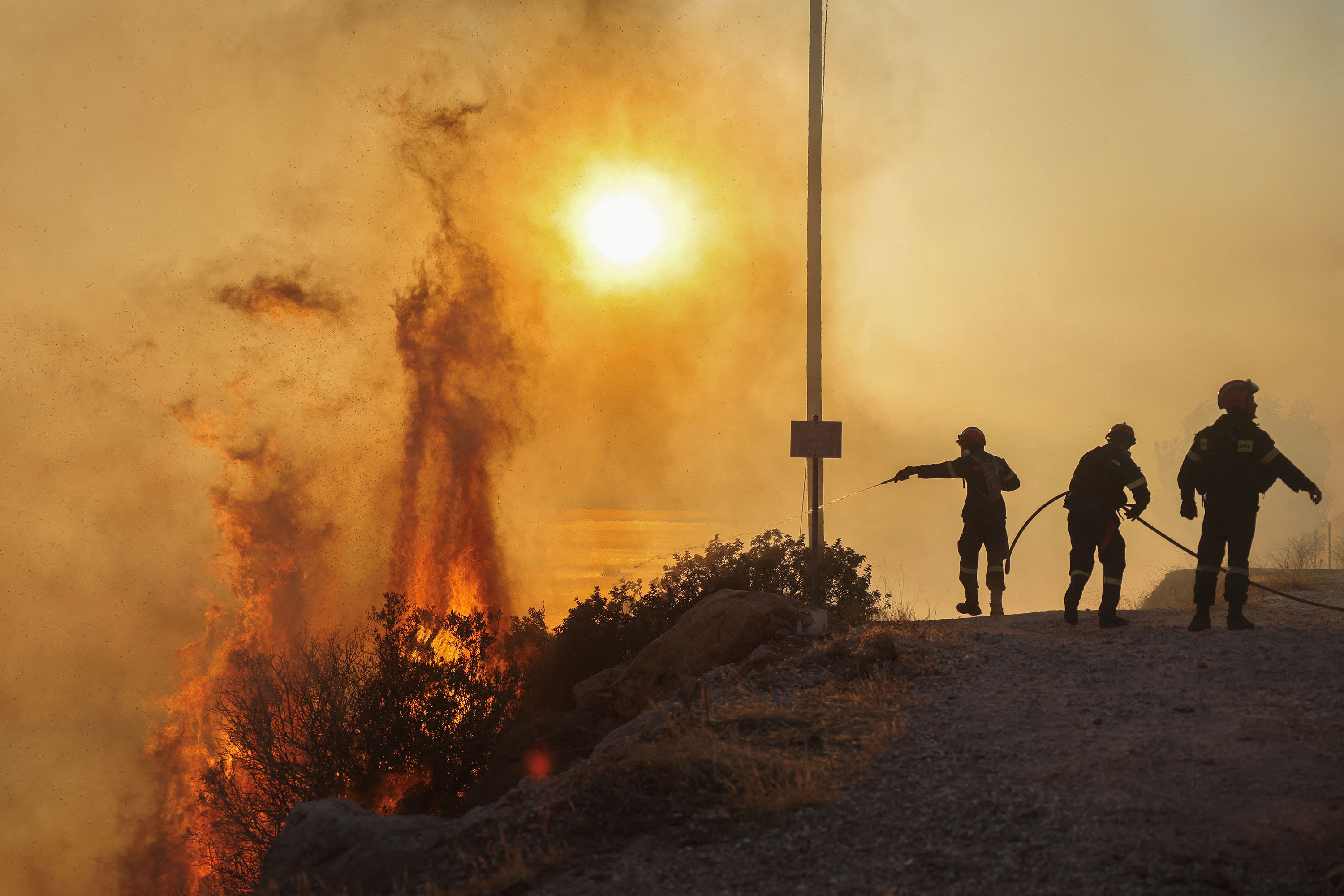 Firefighters try to extinguish a wildfire burning in Saronida, Greece, on Monday.