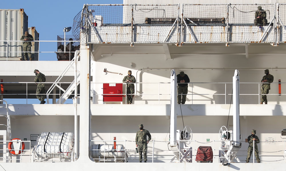 Military personnel stand wearing face masks aboard the USNS Mercy Navy hospital ship docked in the Port of Los Angeles amid the coronavirus pandemic on April 15, in San Pedro, California.