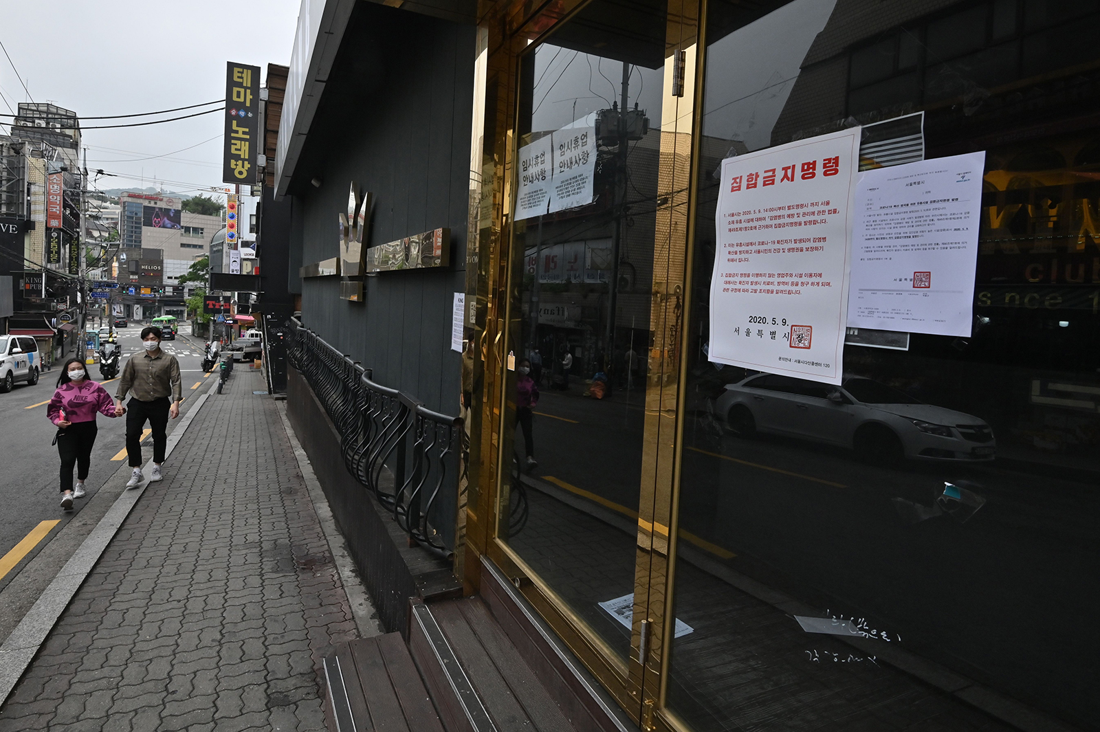 A couple wearing face masks walk past a closed night club in the popular nightlife district of Itaewon in Seoul on May 10.