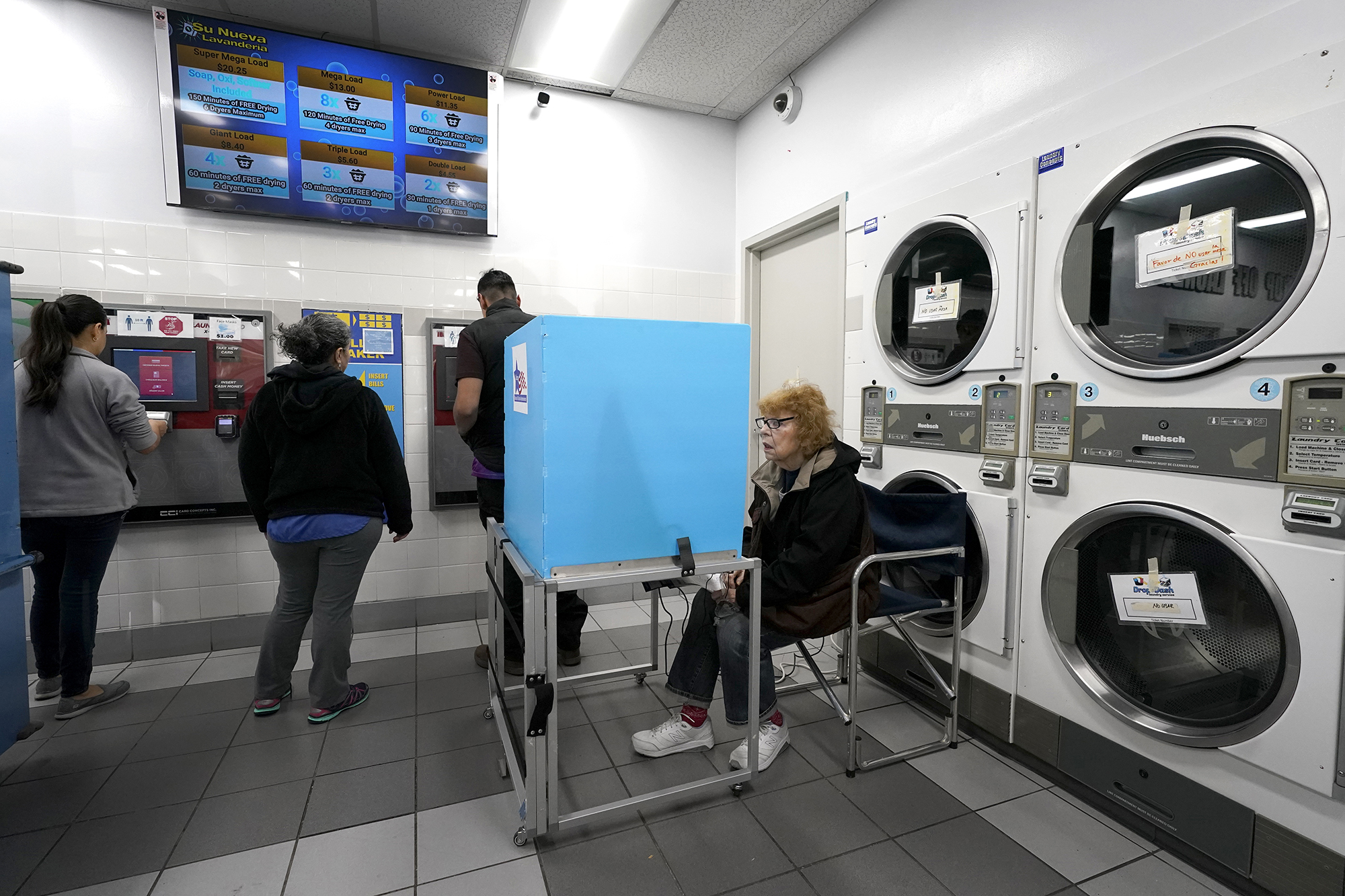 Jeanette Buchanan works on her electronic ballot as patrons at the Su Nueva Lavanderia put cash on laundry cards near Chicago's Midway Airport Tuesday. (AP Photo/Charles Rex Arbogast)