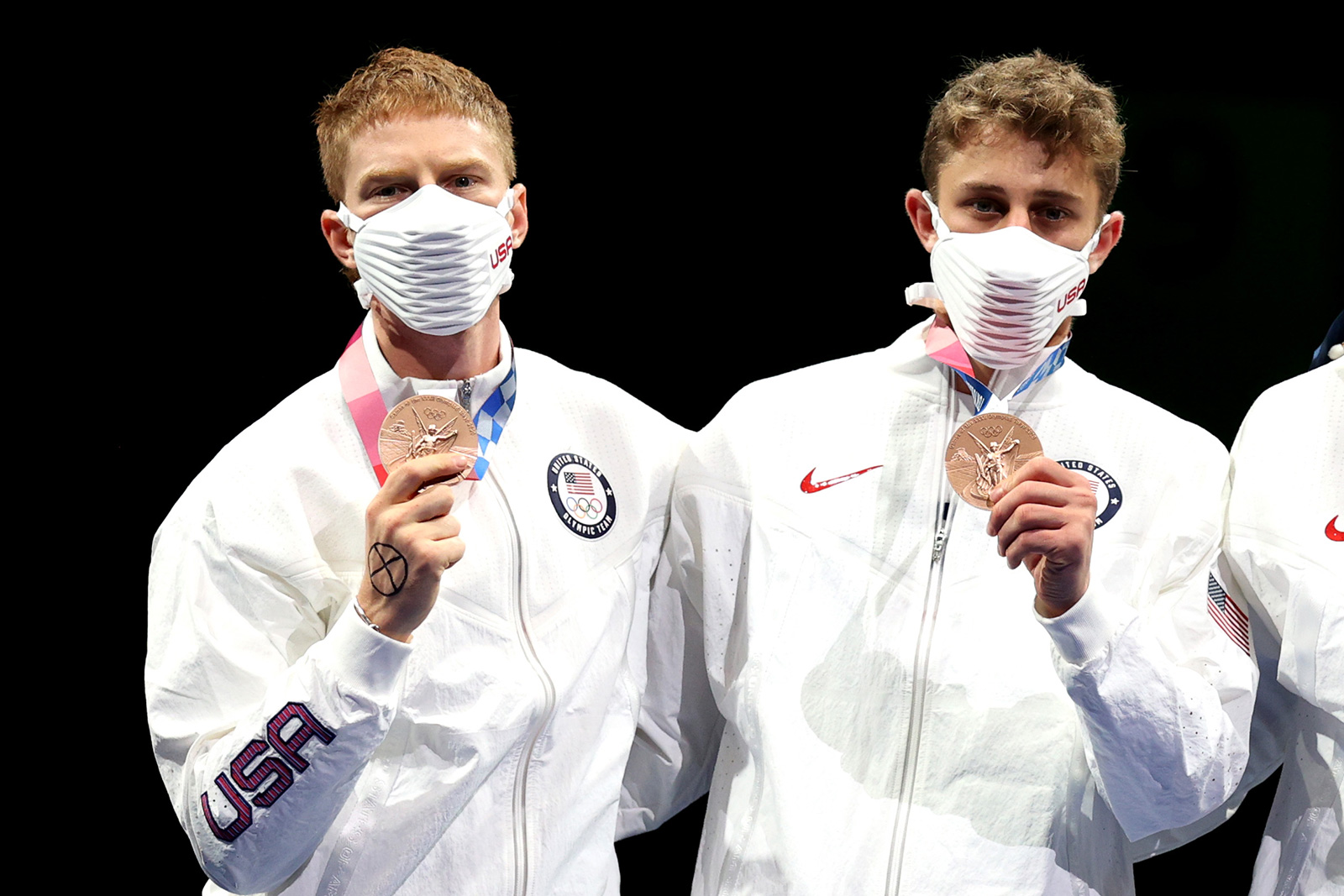 Bronze medalist Race Imboden, left, holds up his medal on the podium during the medal ceremony for the men's team foil event on August 1. 