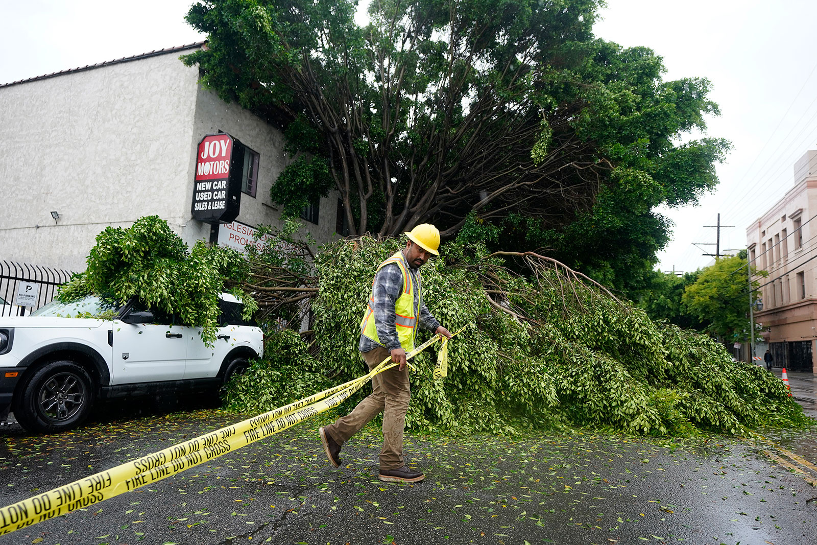 A worker drags caution tape to block off a road after a tree fell in Los Angeles on August 20.