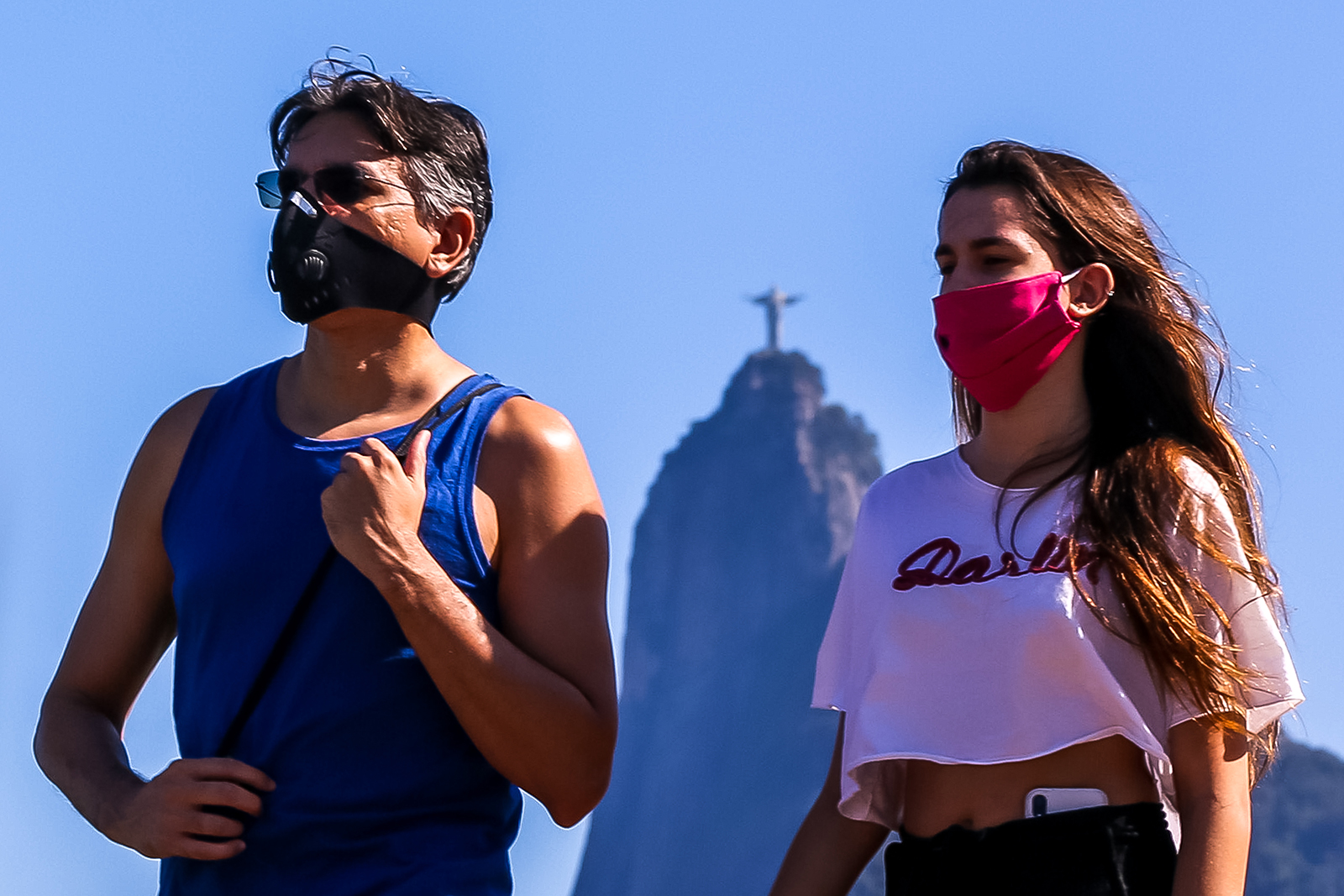 People wearing face masks enjoy the weather at Botafogo Cove, as the Christ the Redeemer statue is seen in the distance, on July 5, in Rio de Janeiro, Brazil.