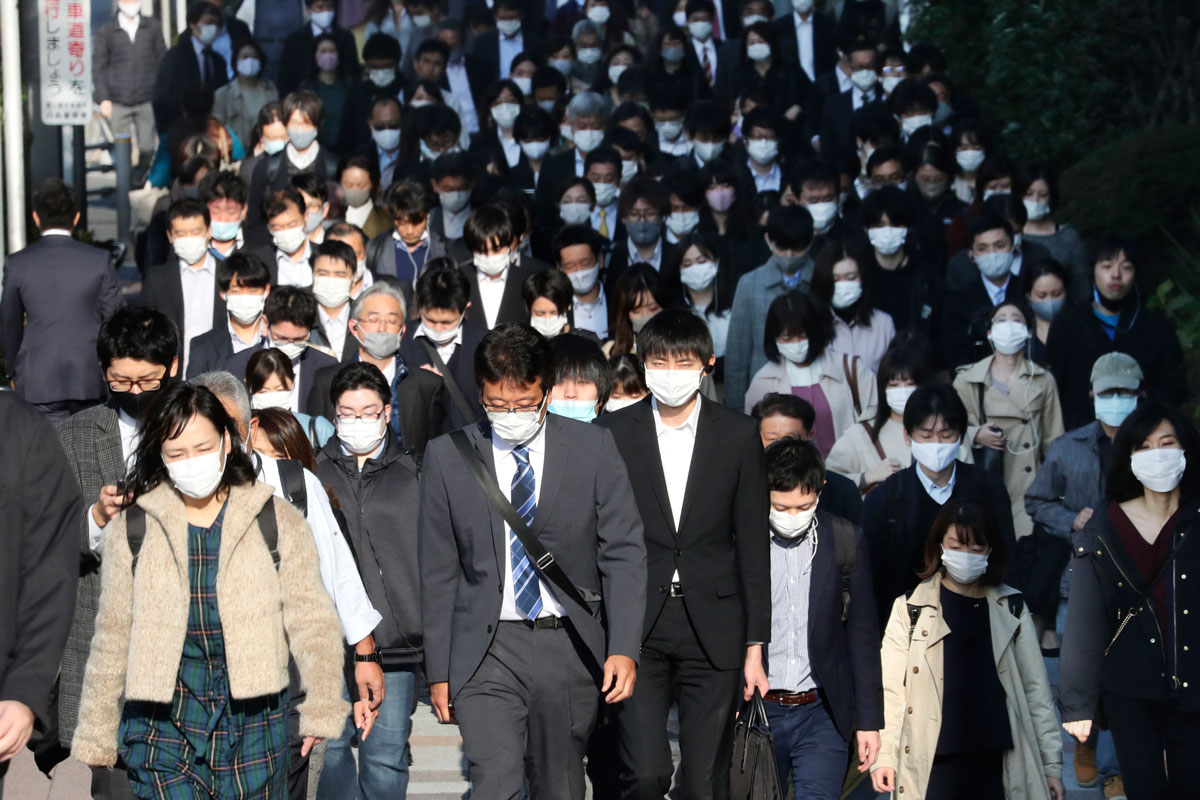 Commuters wearing face masks to protect against the spread of the coronavirus walk on a street in Tokyo on November 17.
