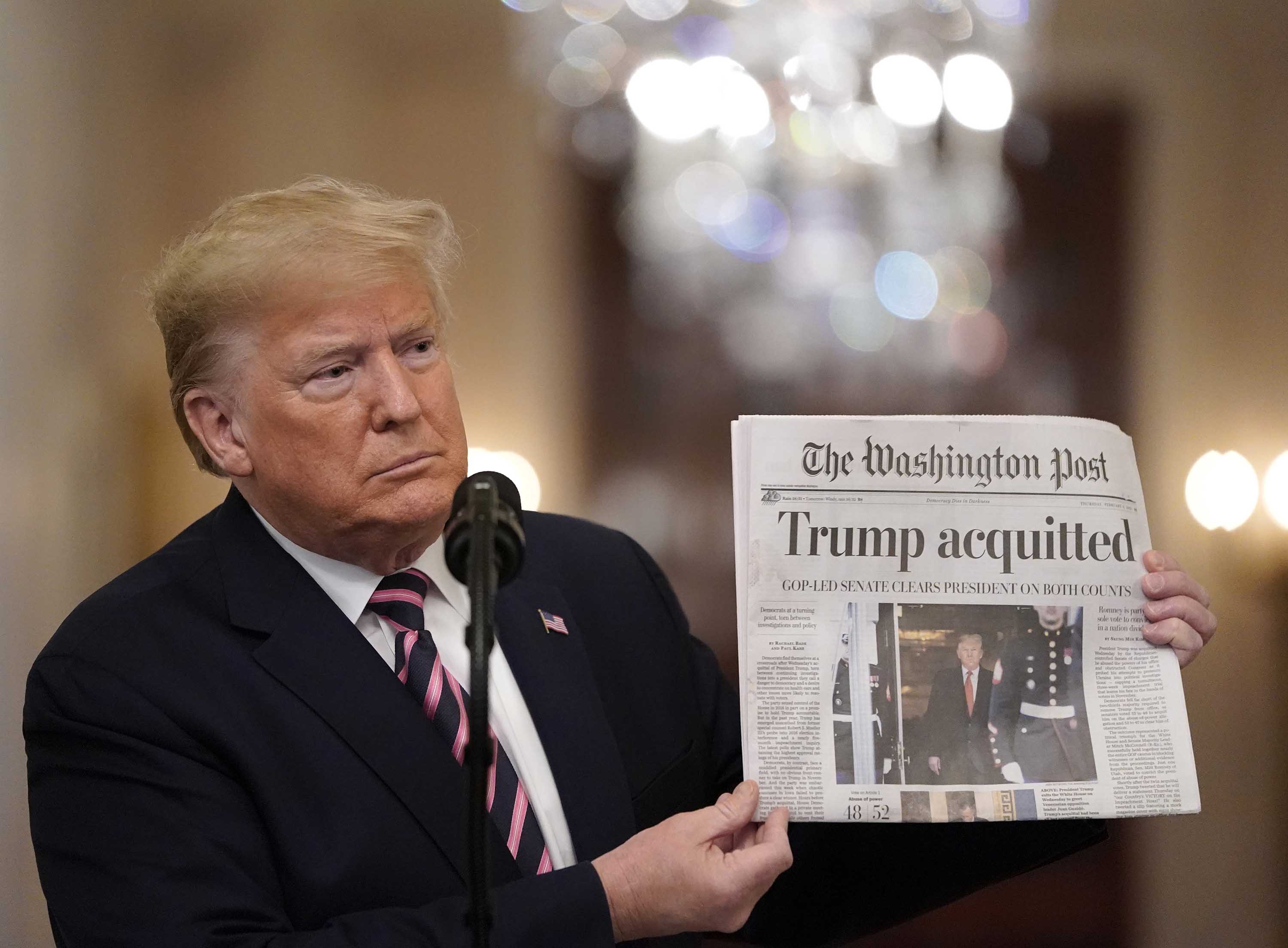 President Donald Trump holds a copy of The Washington Post as he speaks in the White House, one day after the U.S. Senate acquitted on two articles of impeachment, on February 6, 2020.