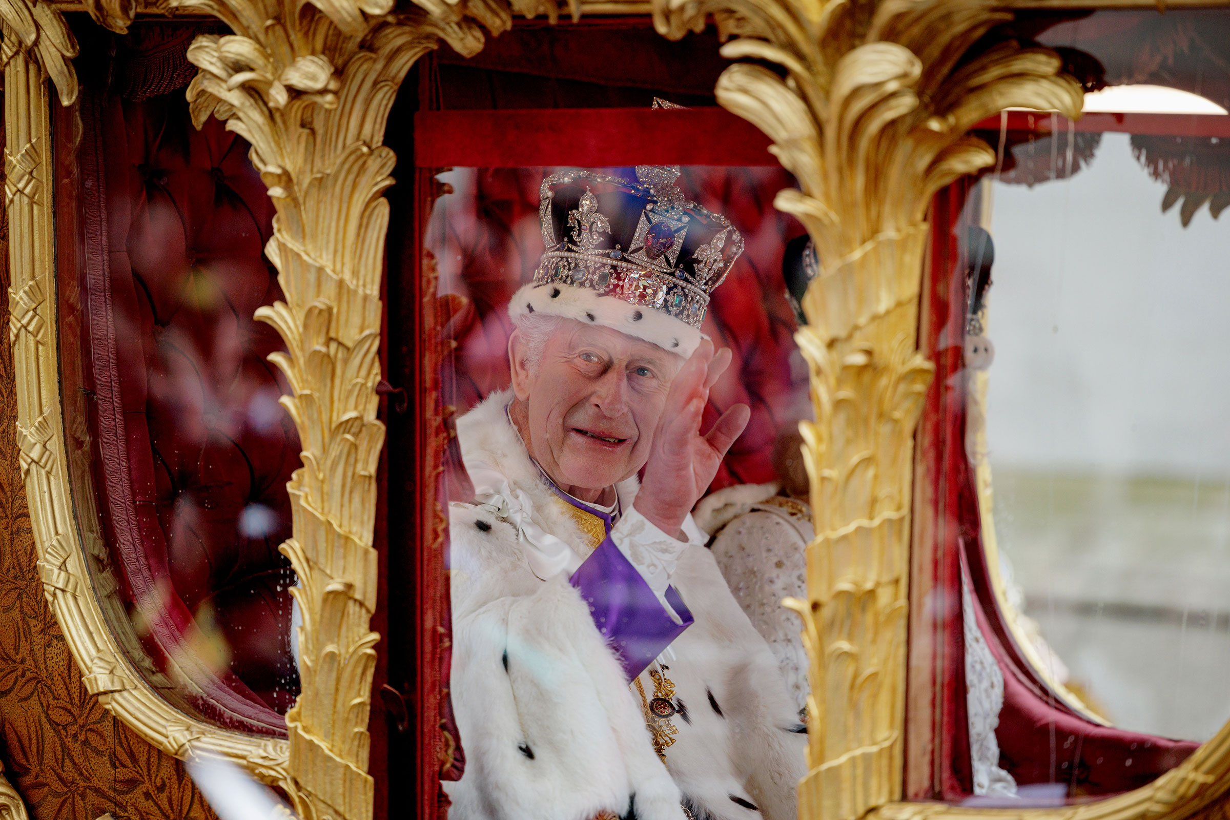 King Charles III waves from the Gold State Coach.