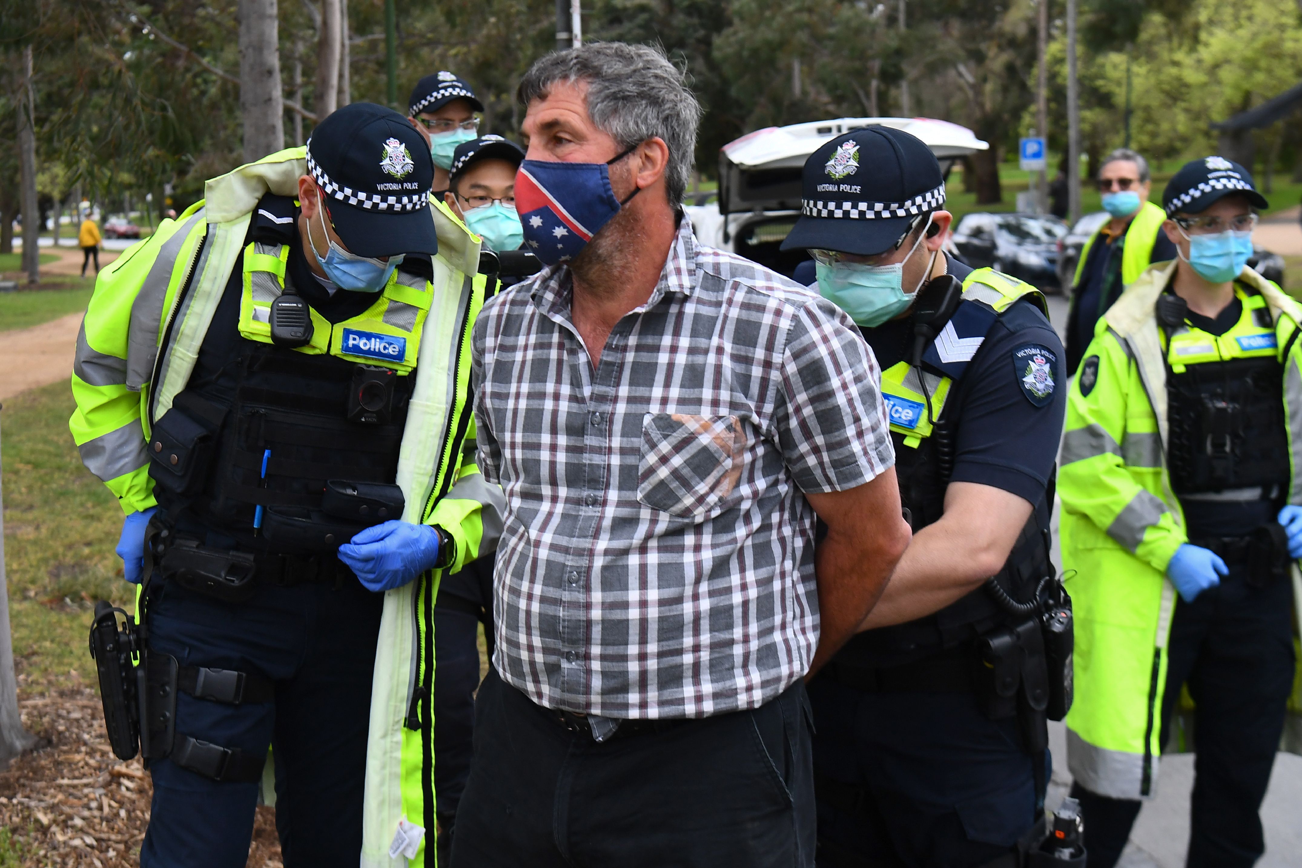 Police detain a protester during an anti-lockdown rally in Melbourne on September 12, 2020.