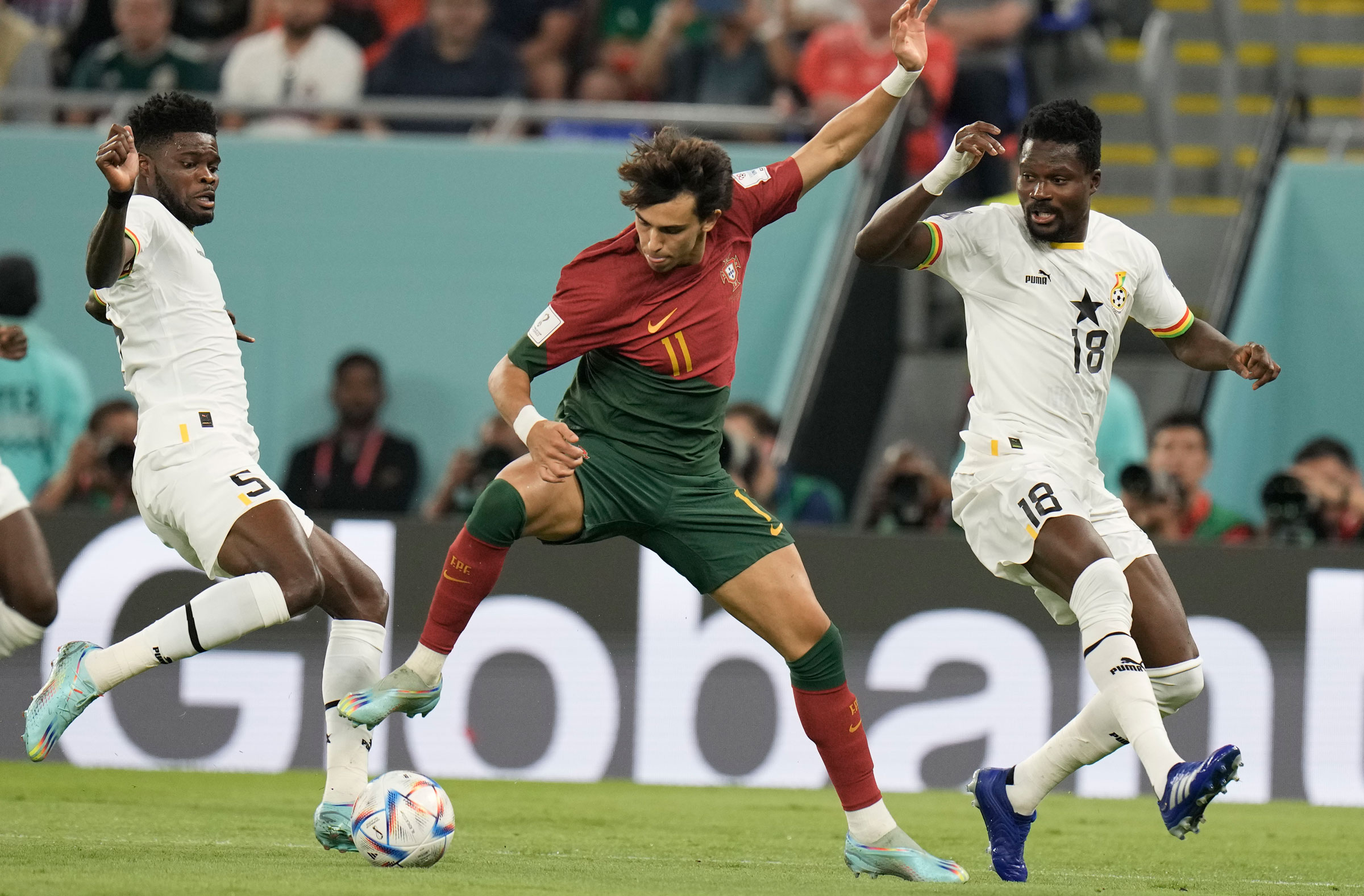 Portugal's Joao Felix is challenged for the ball by Ghana's Thomas Partey, left, and Daniel Amartey.