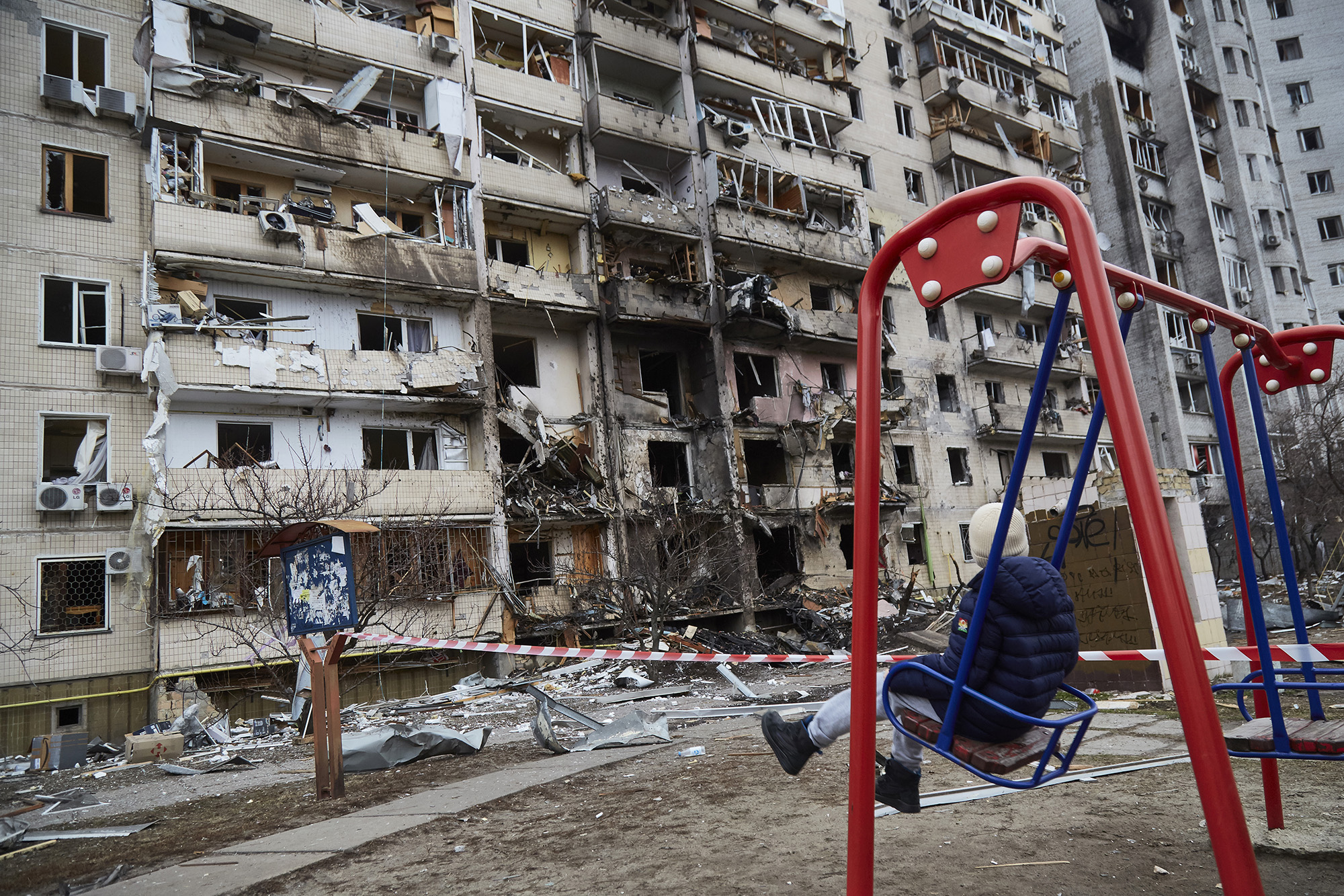 A child on a swing outside a residential building damaged by a missile on February 25, in Kyiv, Ukraine. 