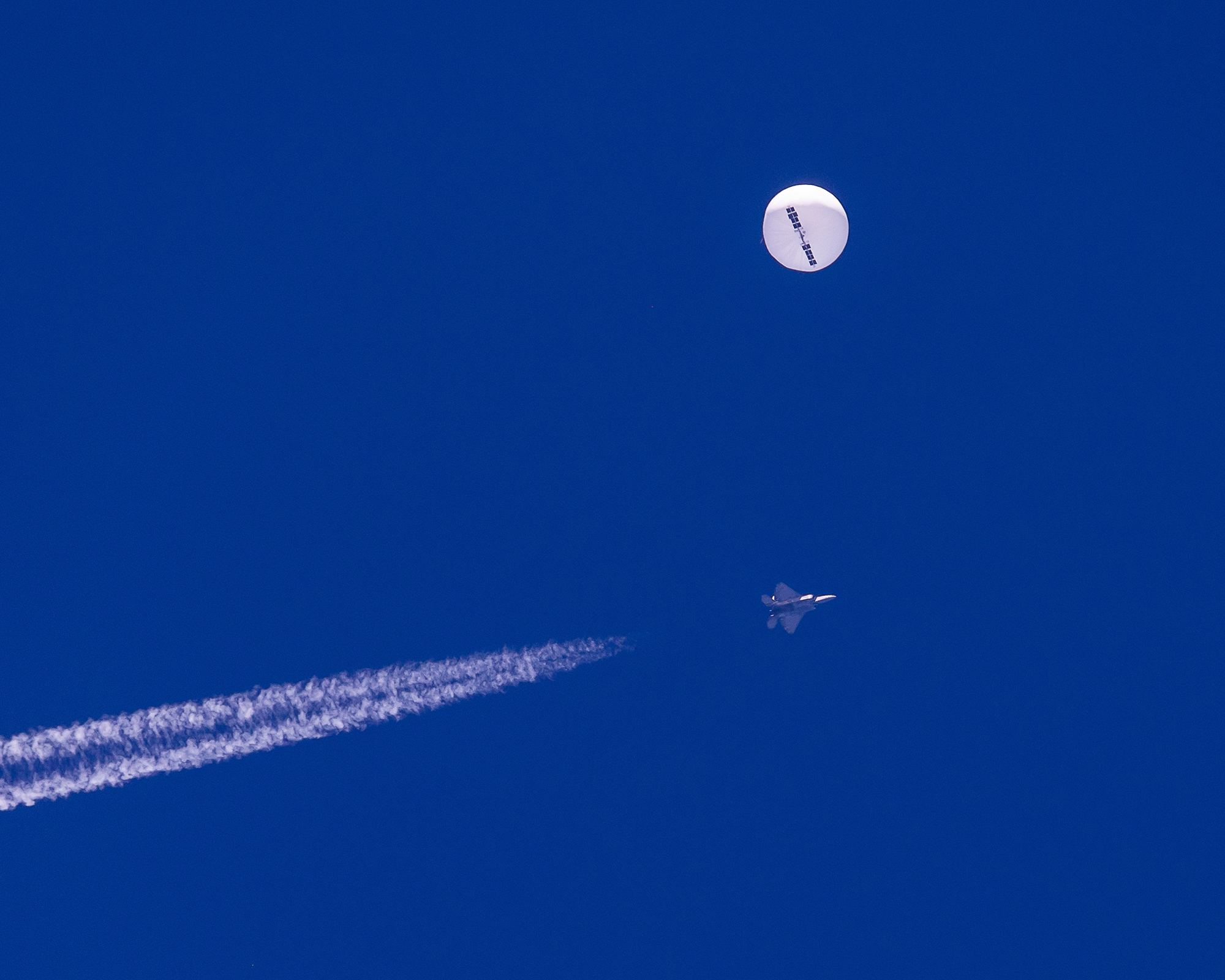 In this photo provided by Chad Fish, a large balloon drifts above the Atlantic Ocean, just off the coast of South Carolina, with a fighter jet and its contrail seen below it on Saturday, February 4. 