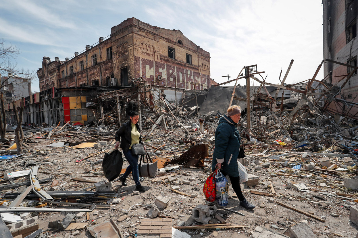 Residents carry their belongings near destroyed buildings in Mariupol, on April 10.