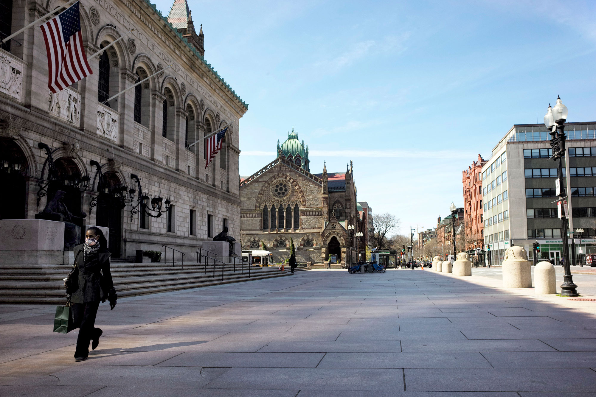 A person wearing a mask out of concern for the coronavirus walks past the Boston Public Library on April 29.