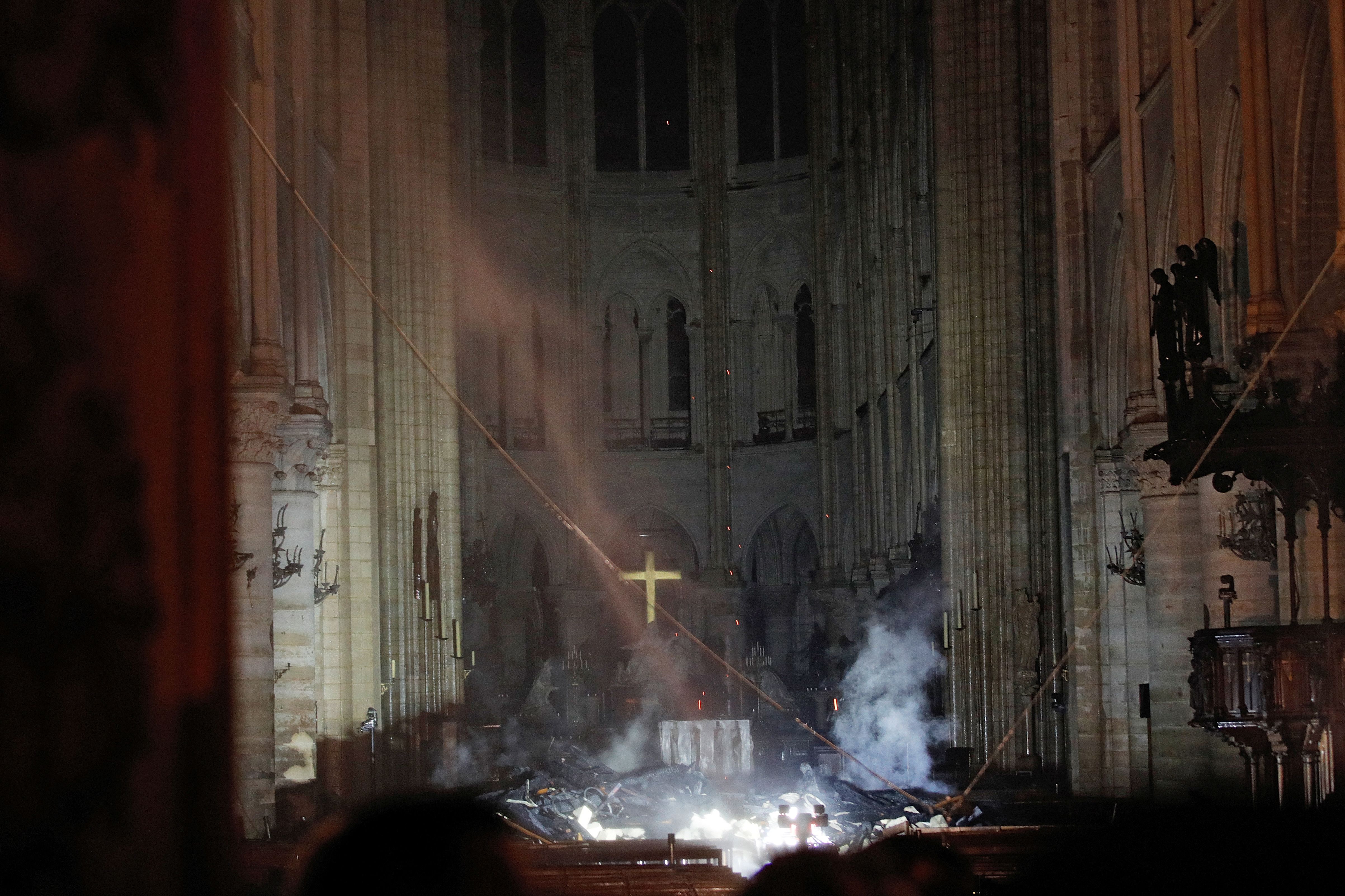 Smoke rises in front of the altar cross at Notre Dame Cathedral after a fire engulfed the building. 