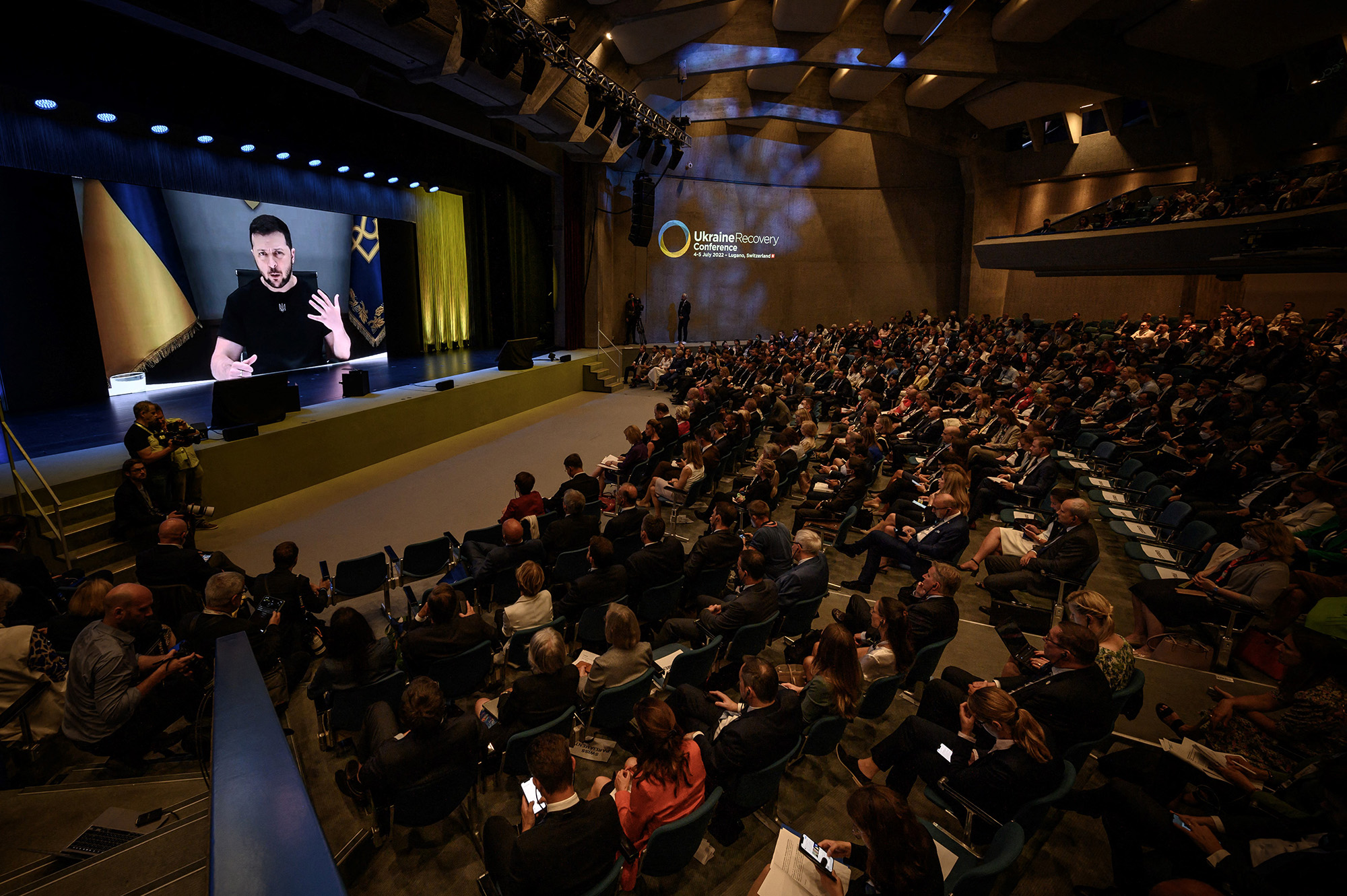 Ukraine's President Volodymyr Zelensky appears on a giant screen as he delivers a statement at the start of a two-day International conference on reconstruction of Ukraine, in Lugano, Switzerland, on July 4.