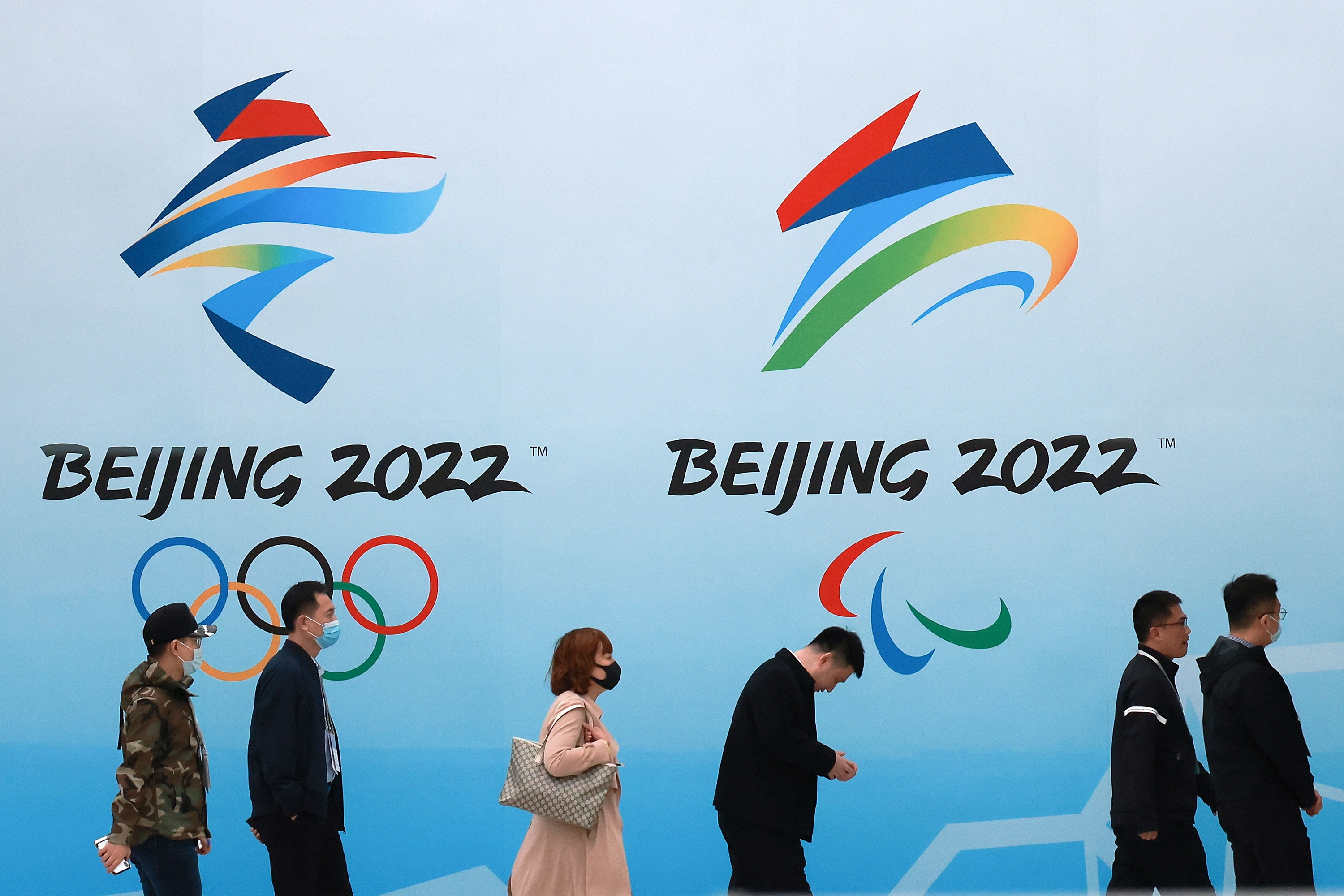 People walk in front of the Beijing 2022 Winter Olympics logos at the National Aquatics Center in Beijing on April 9.