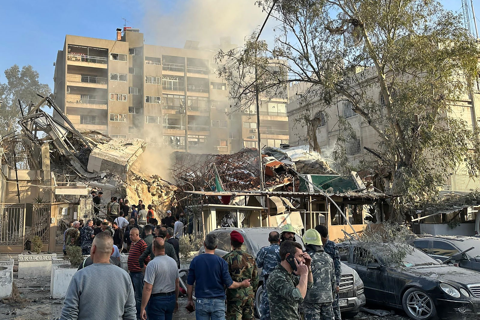 Emergency and security personnel gather at the site of strikes, which hit a building next to the Iranian embassy, in Damascus, Syria, on Monday.