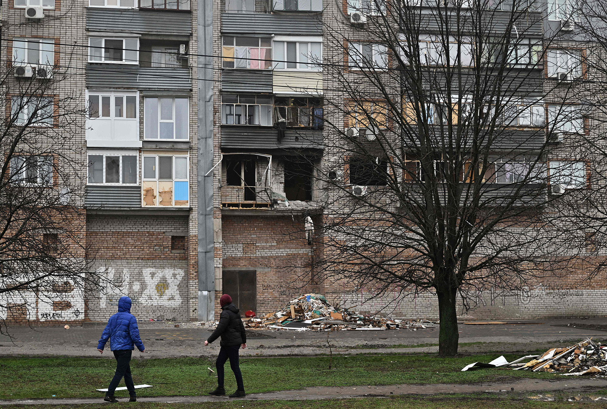 Local residents walk past a damaged building following Russian attacks in the city of Nikopol, Dnipropetrovsk region, on December 12.