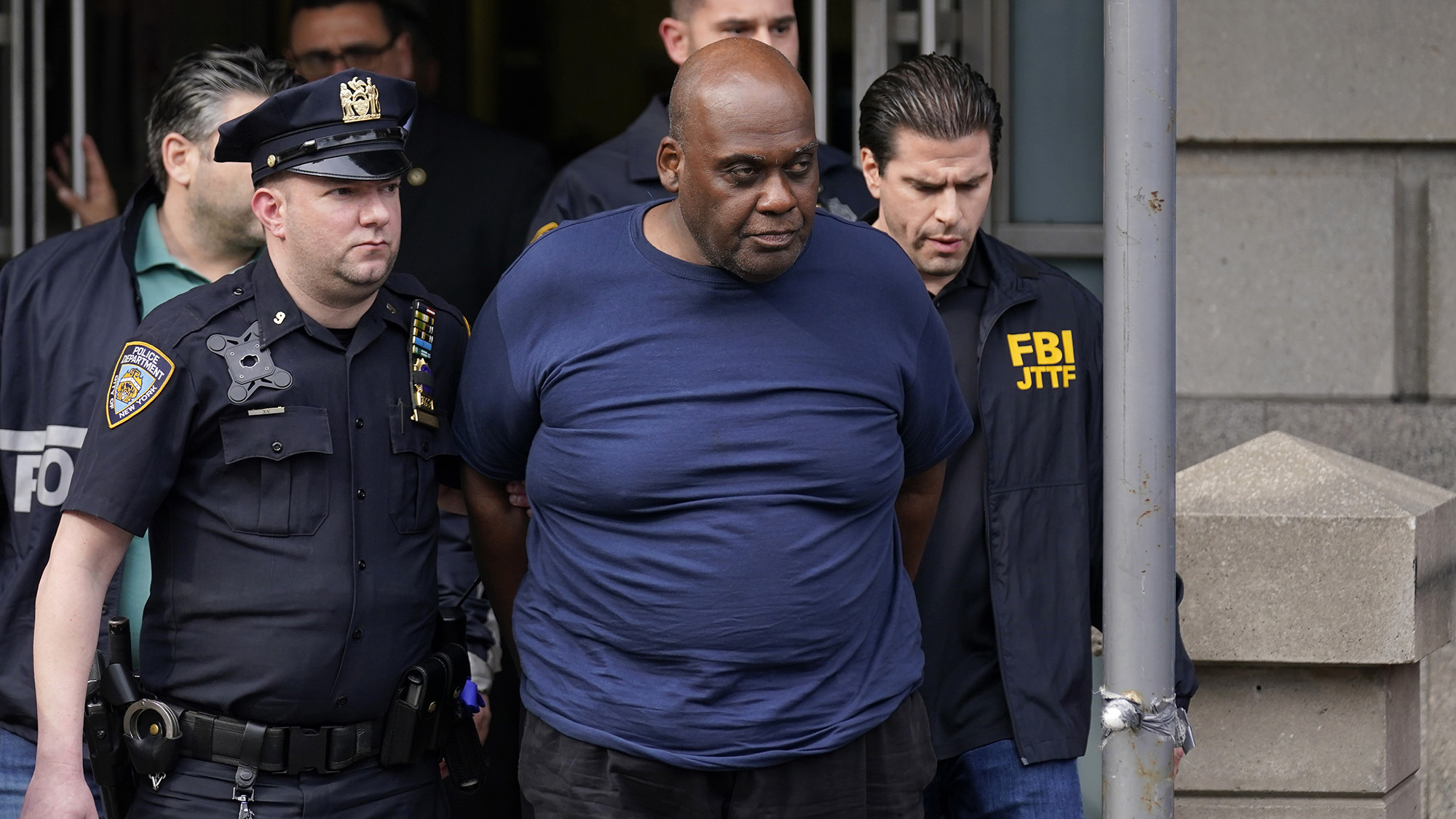 New York City Police and law enforcement officials lead subway shooting suspect Frank R. James, 62, center, away from a police station, in New York on Wednesday, April 13.
