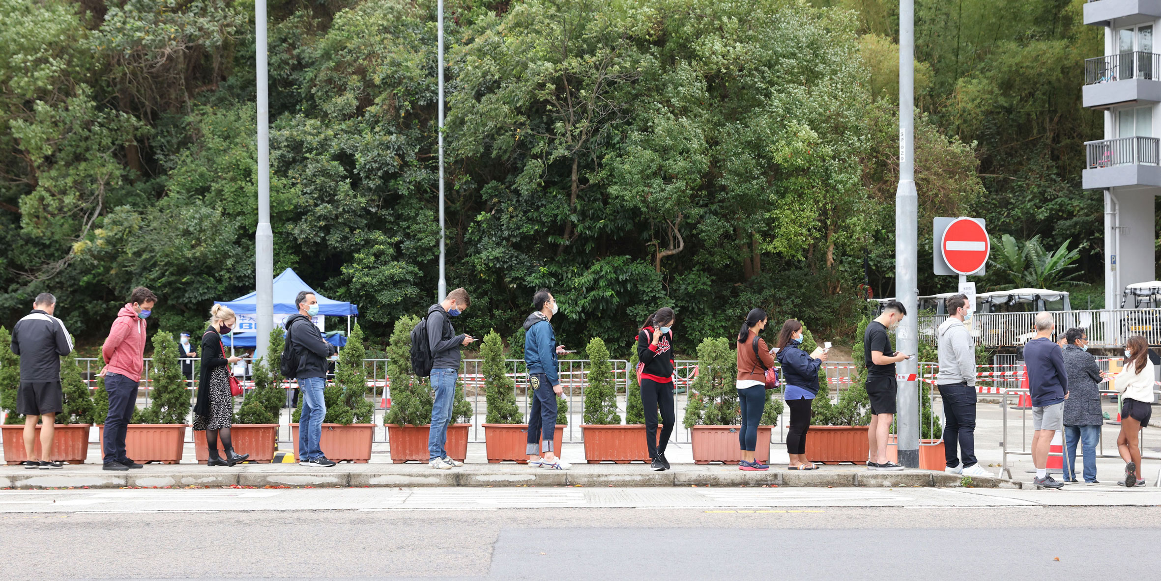 In this file photo, residents and workers of Discovery Bay subject to compulsory testing form a queue near the Discovery Bay Fire Station on Lantau Island, Hong Kong, on Nov. 2021