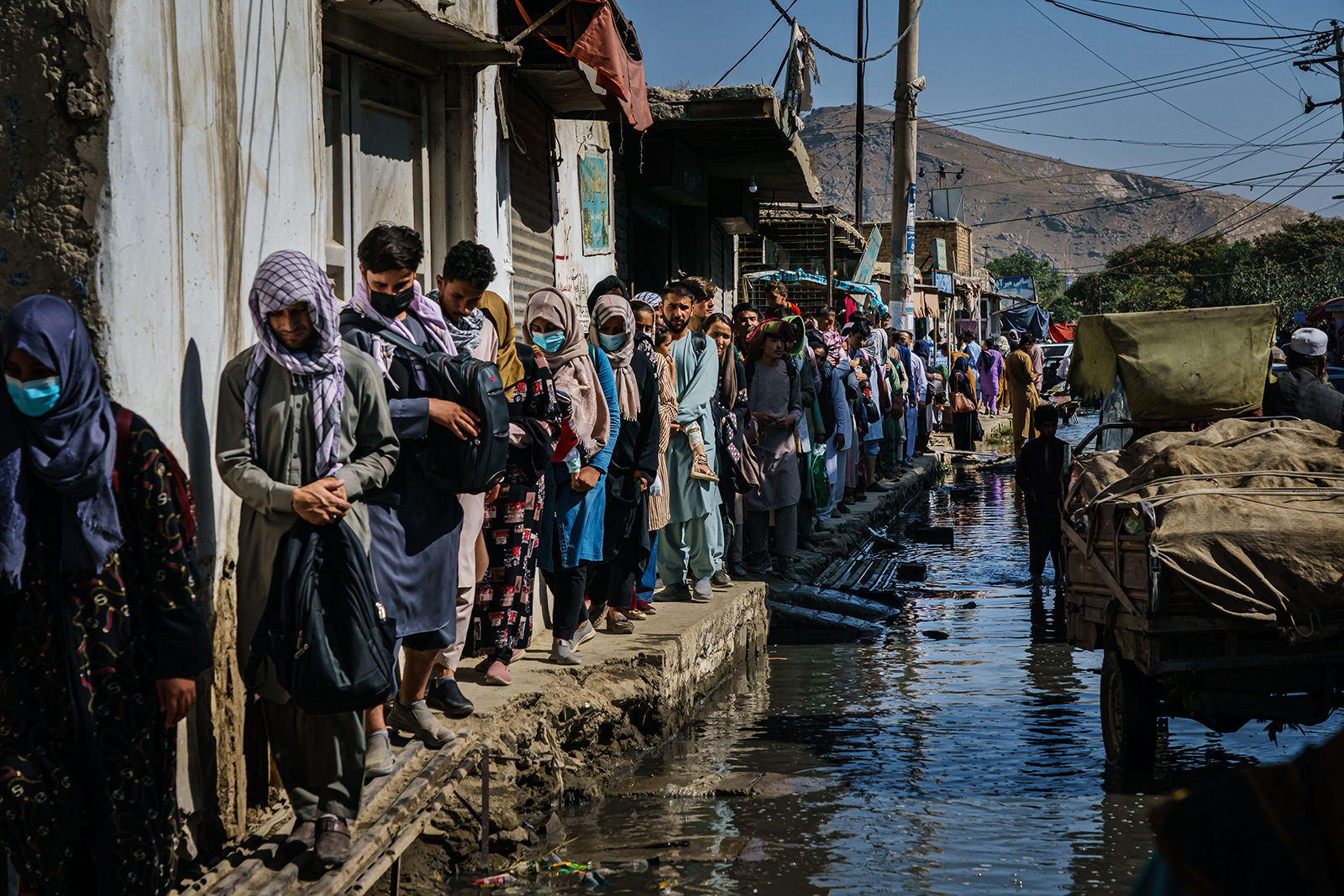 Afghans make their way through a flooded street towards a nearby airport entrance to try their chance at evacuating out of the country, in Kabul, Afghanistan on Wednesday, August 25. 