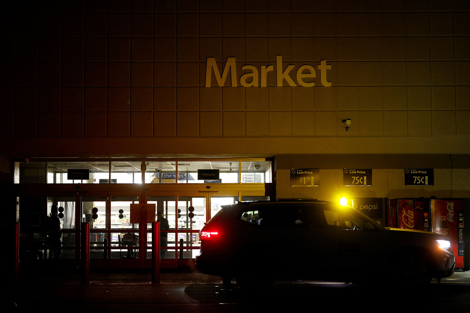 A security patrol car guards the closed entrance to a local Walmart store which was running a generator to light its interior in Aberdeen, North Carolina, on December 4.