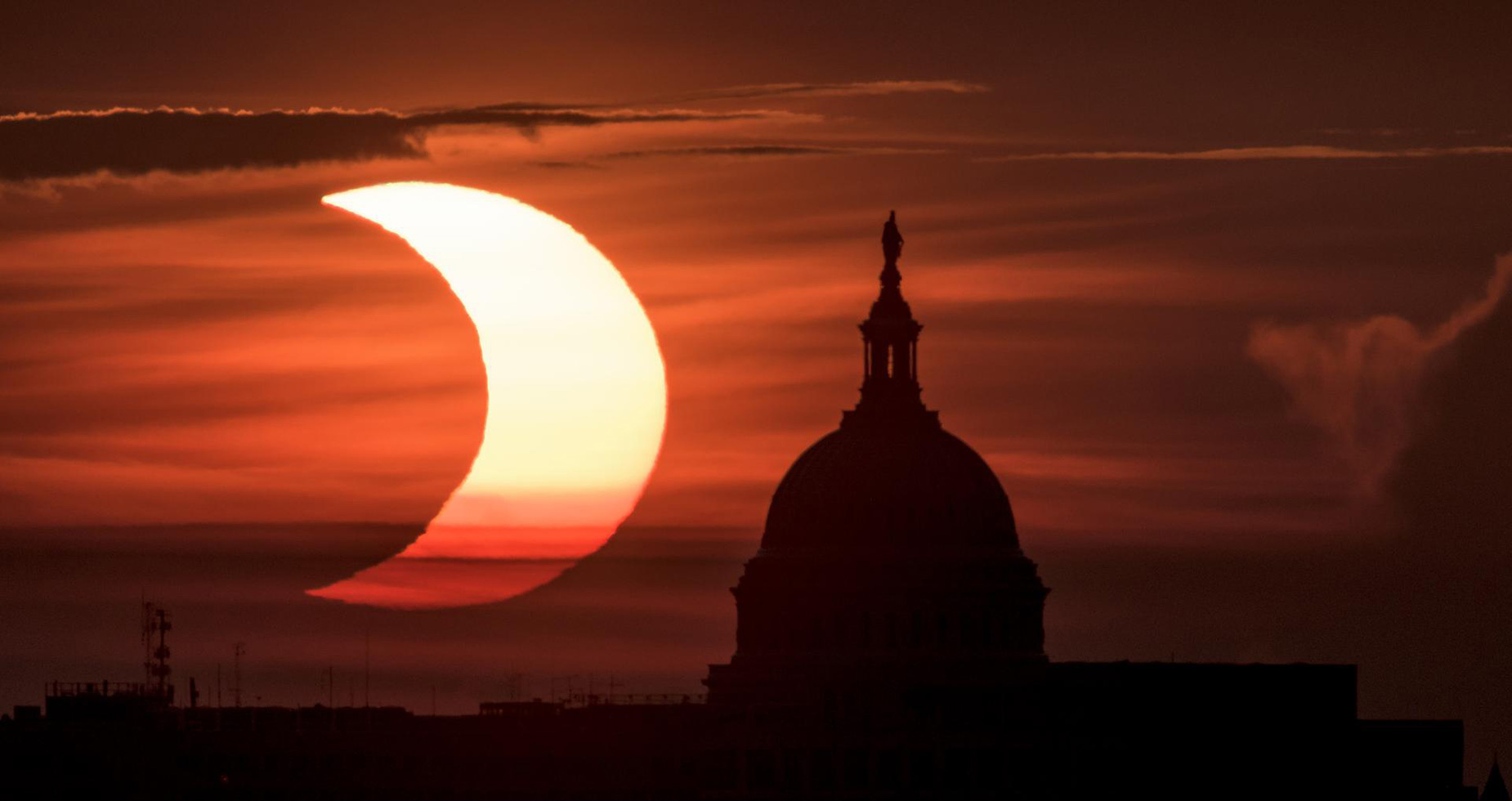 A partial solar eclipse is seen as the sun rises to the left of the US Capitol building in Washington, on June 10, 2021.
