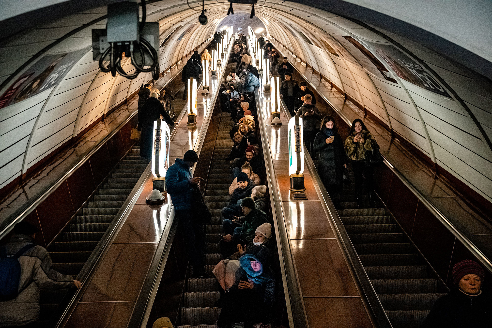 Civilians sit on an escalator while take shelter inside a metro station during an air raid alert in the centre of Kyiv on December 16.